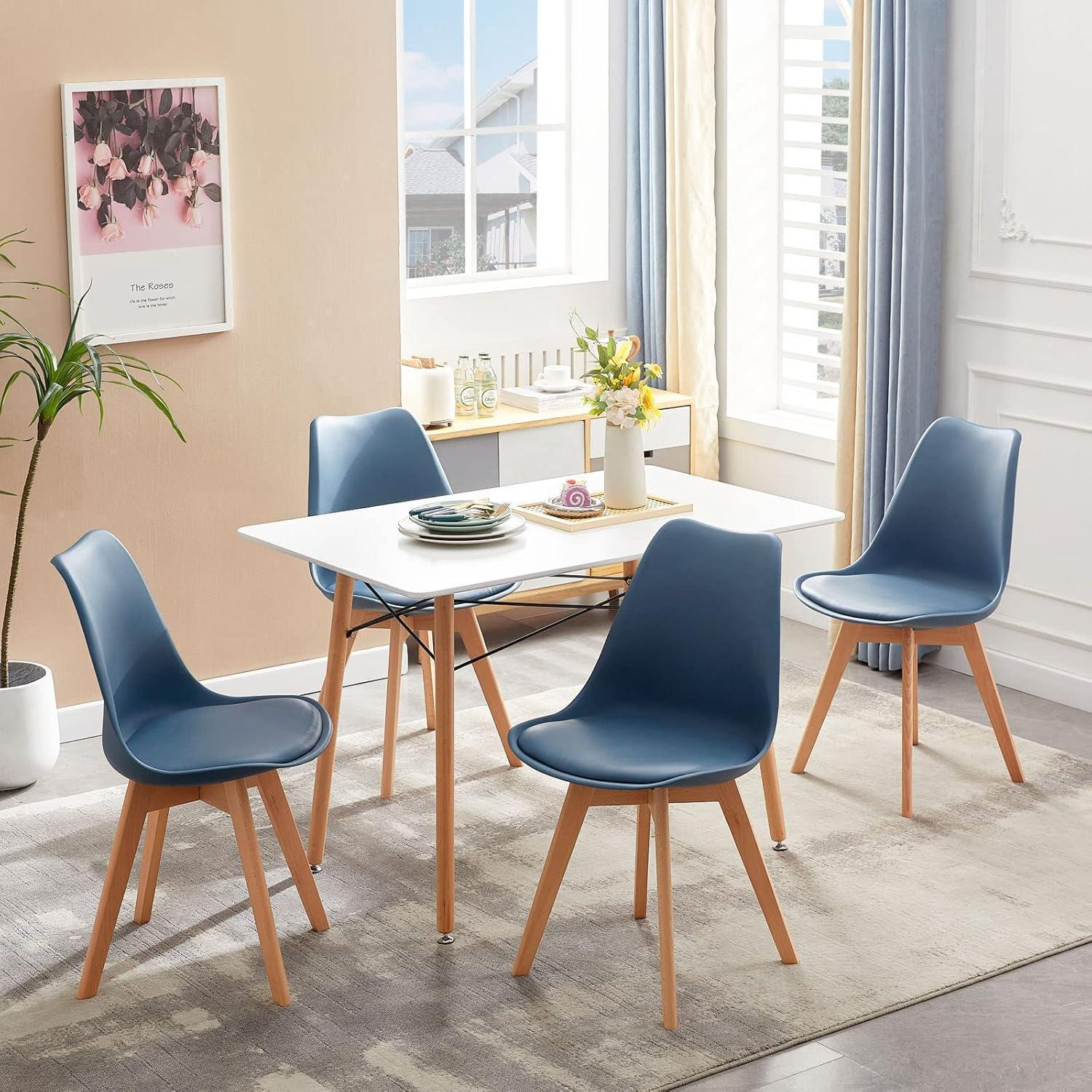 Una luminosa zona pranzo con tavolo bianco, quattro sedie blu, gambe in legno e un tappeto.