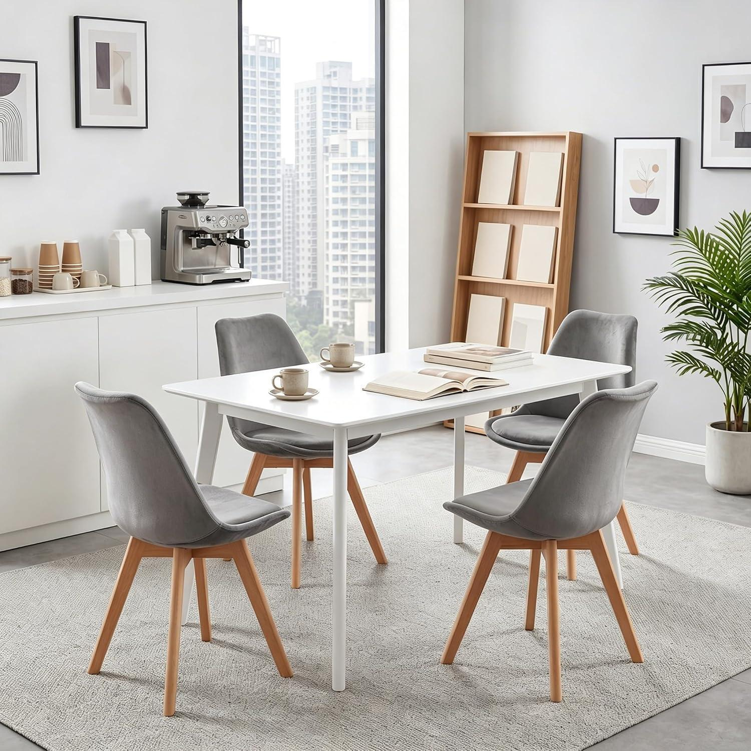 Zona pranzo moderna con tavolo bianco, quattro sedie grigie con gambe in legno, macchina da caffè e vista.