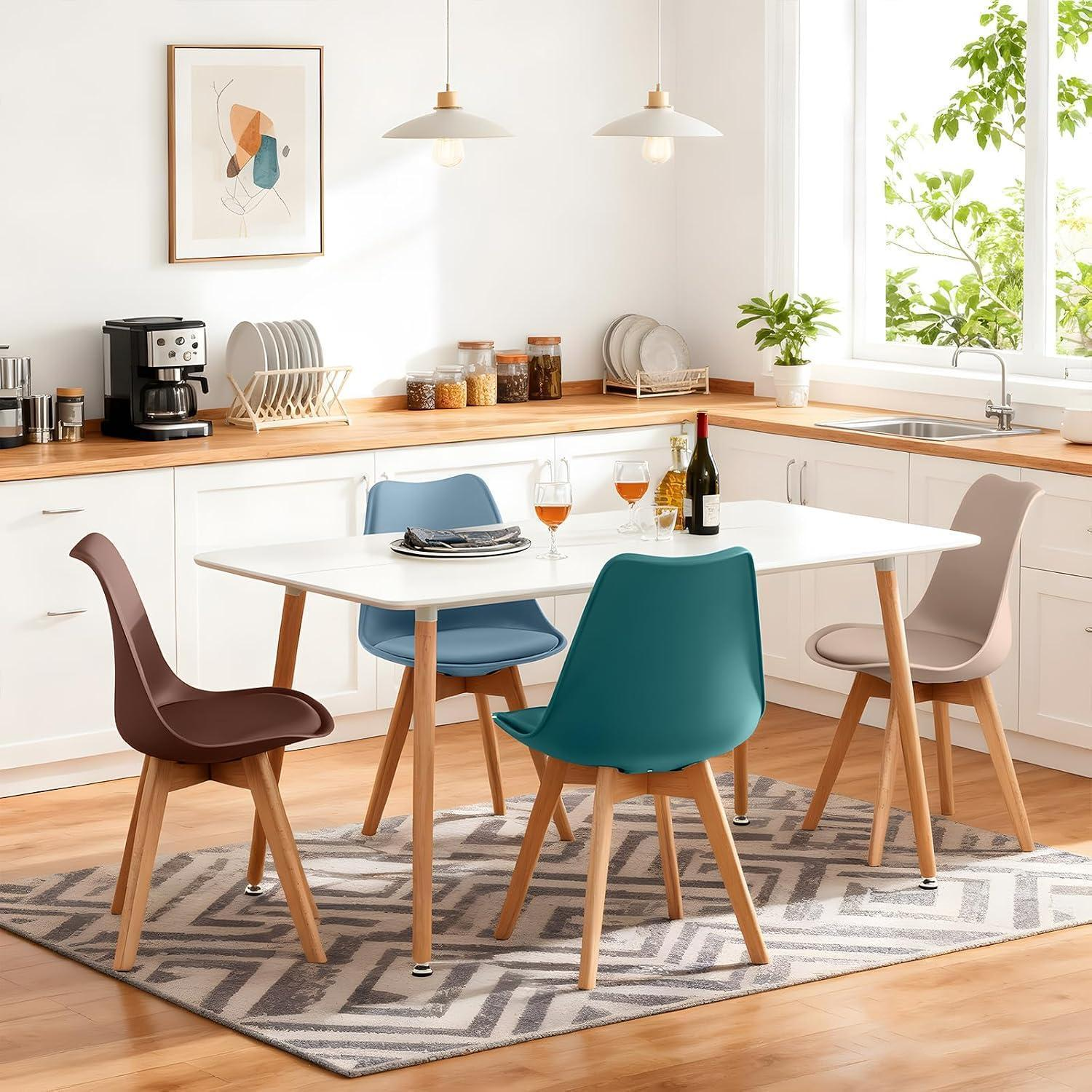 Un tavolo da pranzo bianco con sedie colorate in una cucina luminosa.