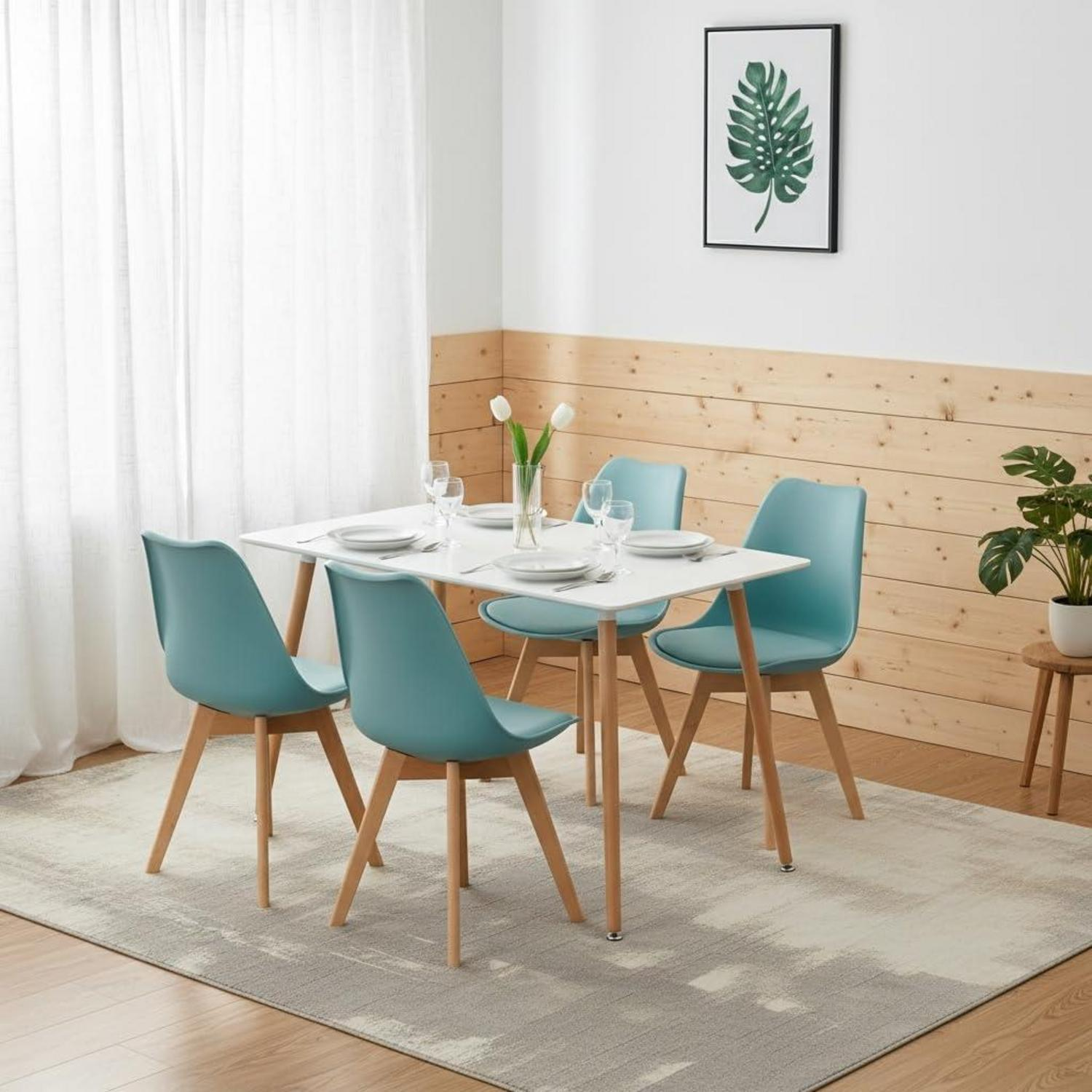 Un tavolo da pranzo bianco con quattro sedie turchesi su un tappeto fantasia, davanti a una parete in legno.