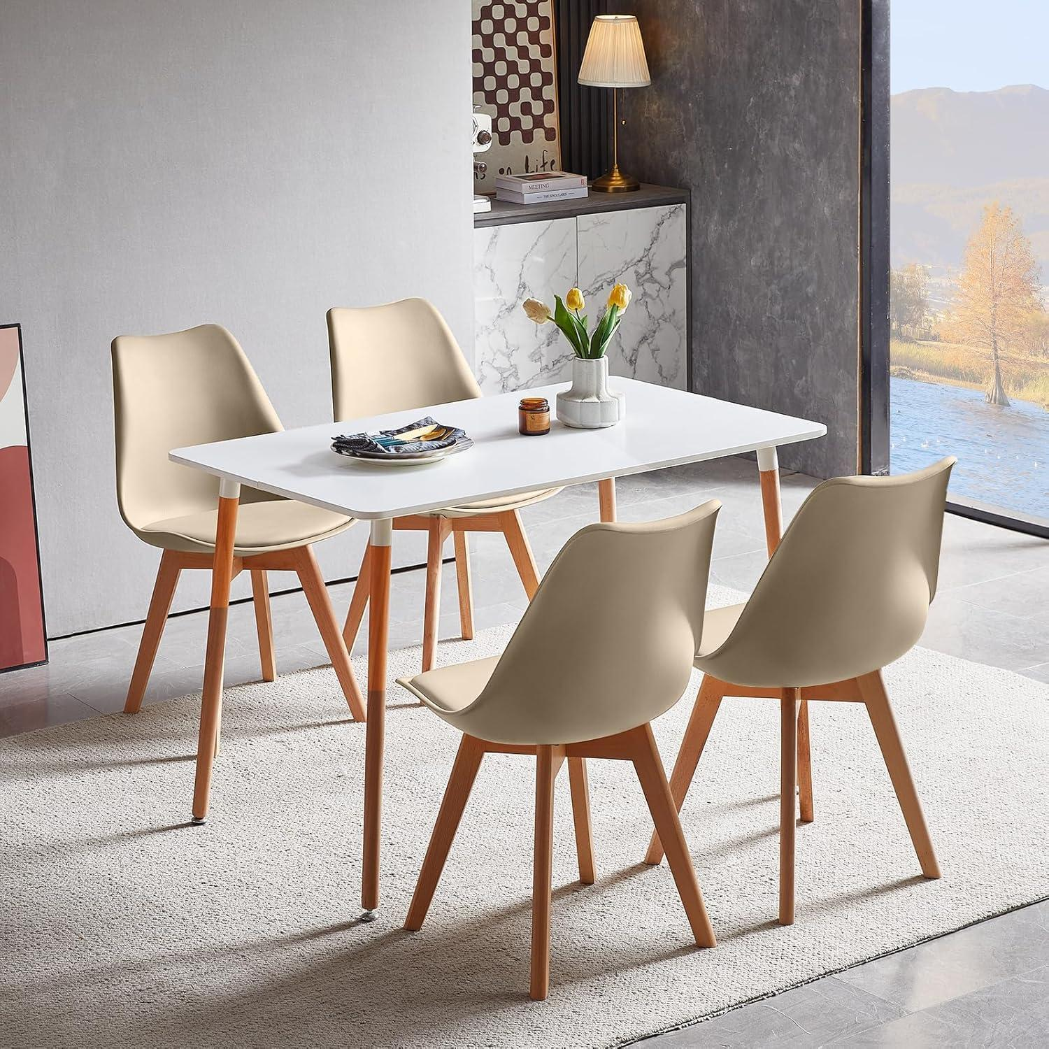 Un tavolo da pranzo bianco con quattro sedie beige e gambe in legno su un tappeto in una stanza moderna con finestra.