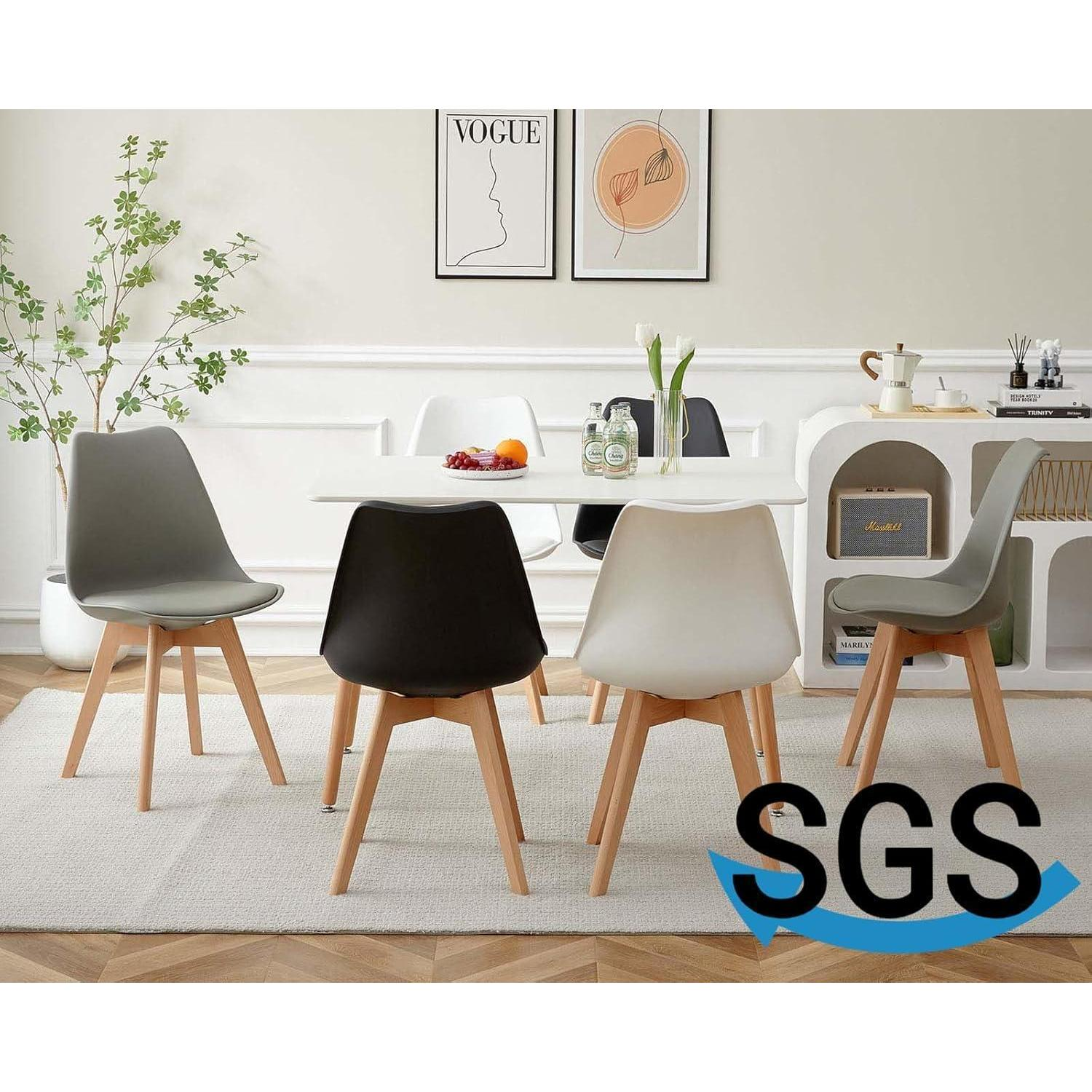 Una sala da pranzo moderna con un tavolo bianco, quattro sedie di diversi colori, una pianta e due poster.