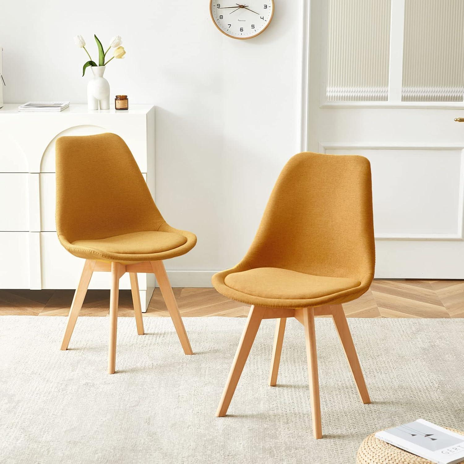 Due sedie giallo senape con gambe in legno su un tappeto chiaro in una stanza bianca moderna.