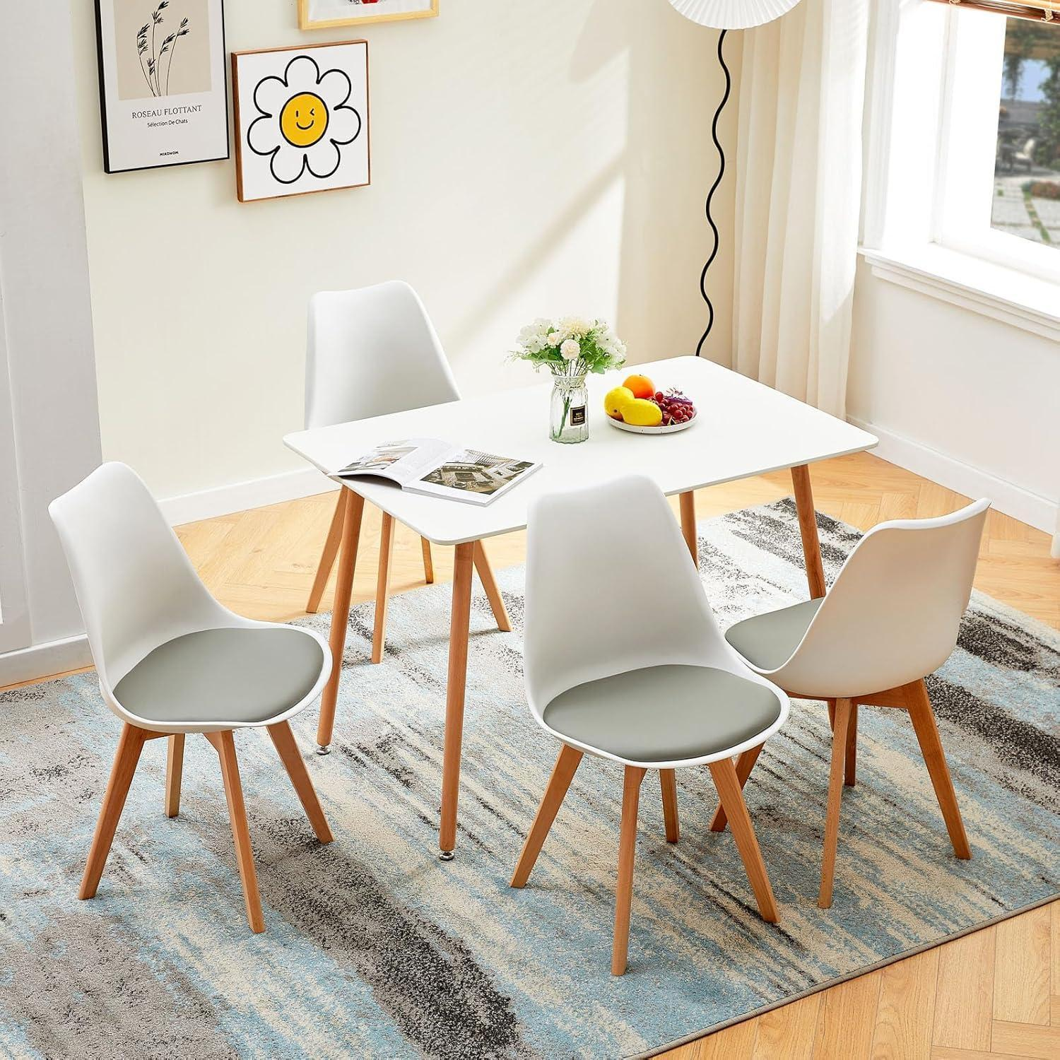 Un tavolo da pranzo bianco con quattro sedie grigie e gambe in legno su un tappeto blu-grigio.