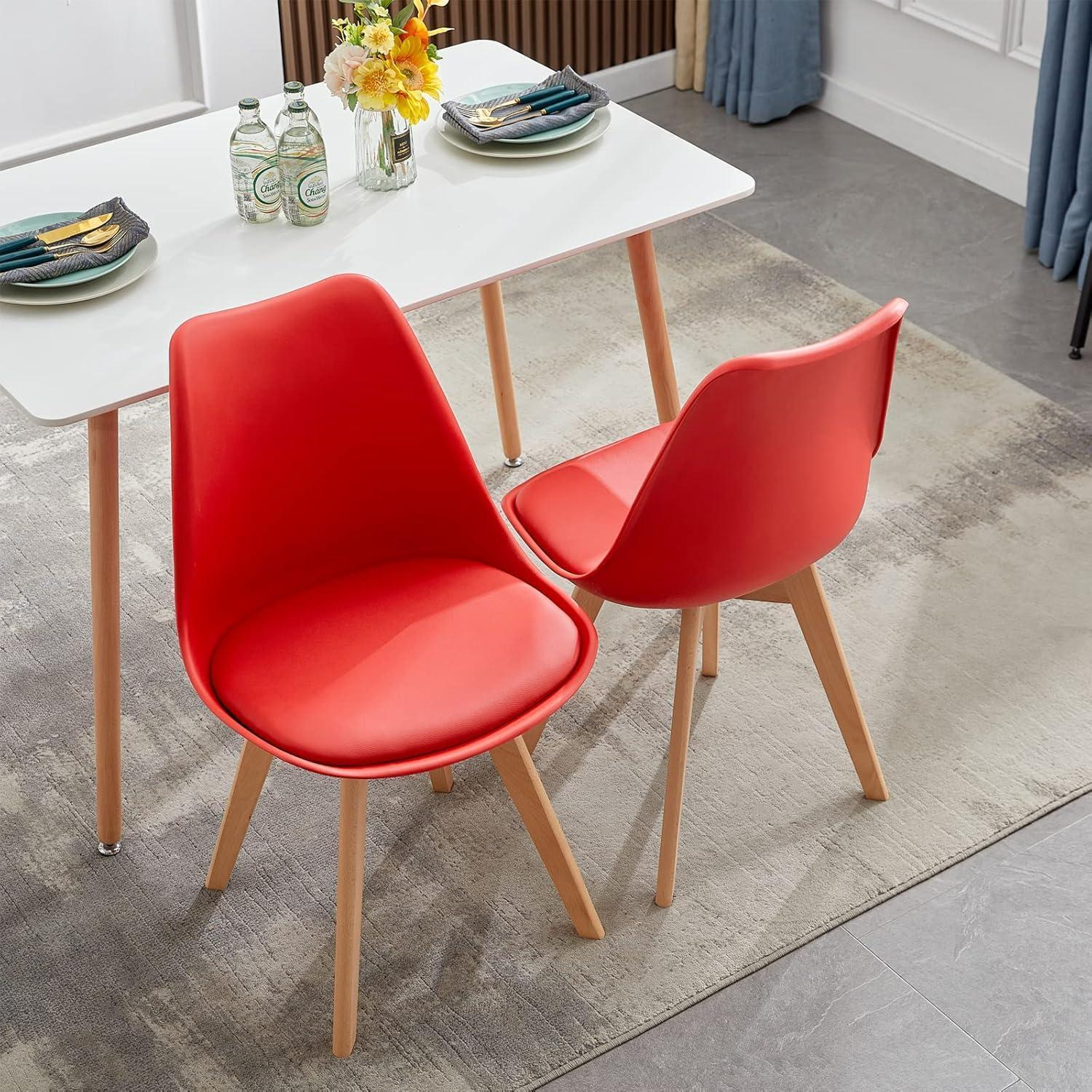 Due sedie rosse con gambe in legno sono posizionate davanti a un tavolo da pranzo bianco su un tappeto grigio.