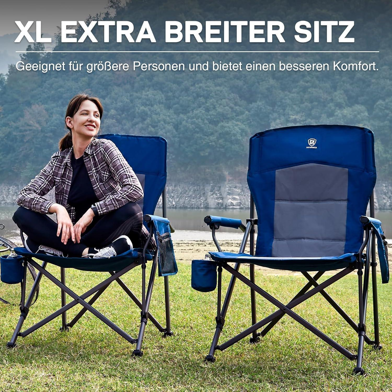 Una donna siede su una sedia da campeggio blu XXL all'aperto, con un'altra sedia e un lago sullo sfondo.