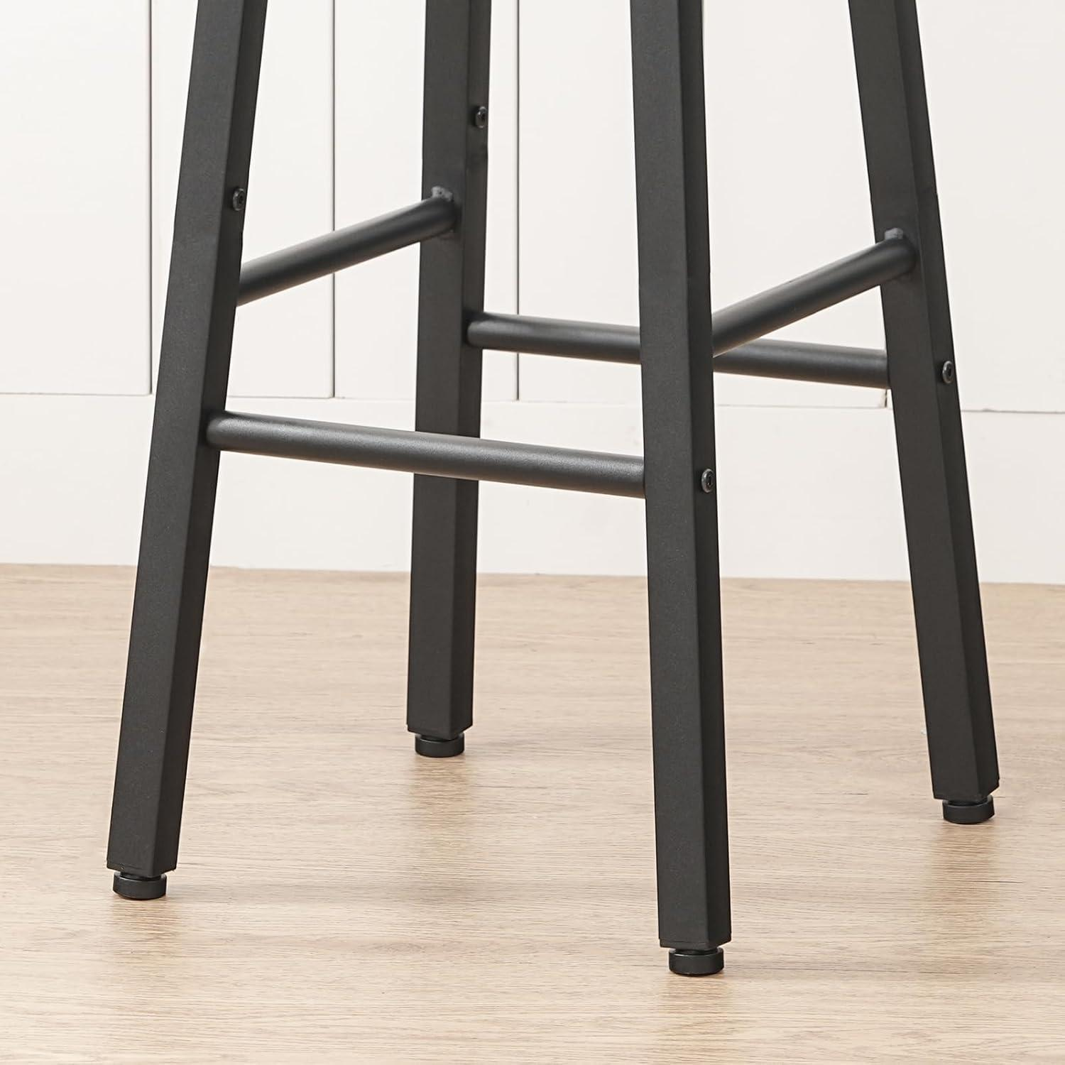 Primo piano di quattro gambe in metallo nero di uno sgabello su pavimento in legno chiaro contro parete bianca.