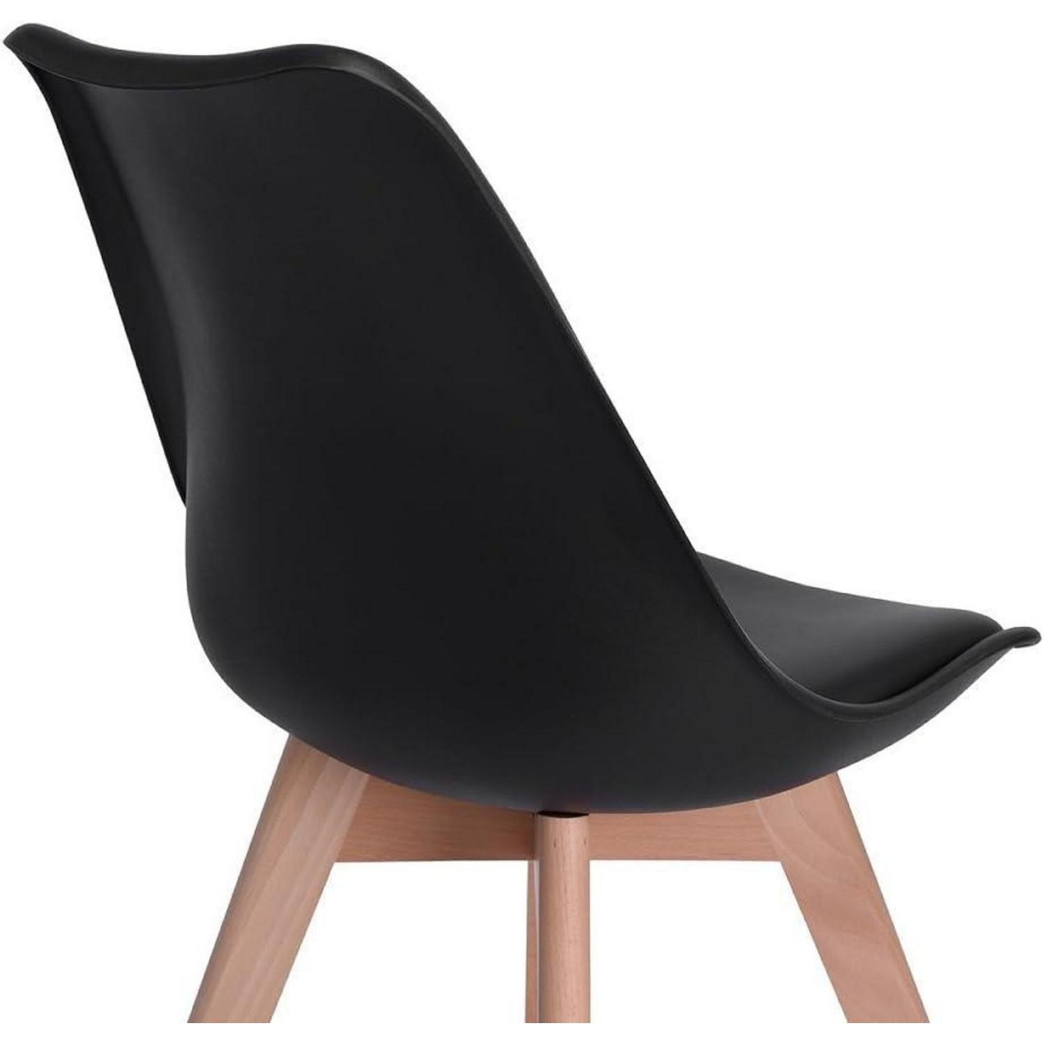 Una sedia nera con gambe in legno su sfondo bianco.