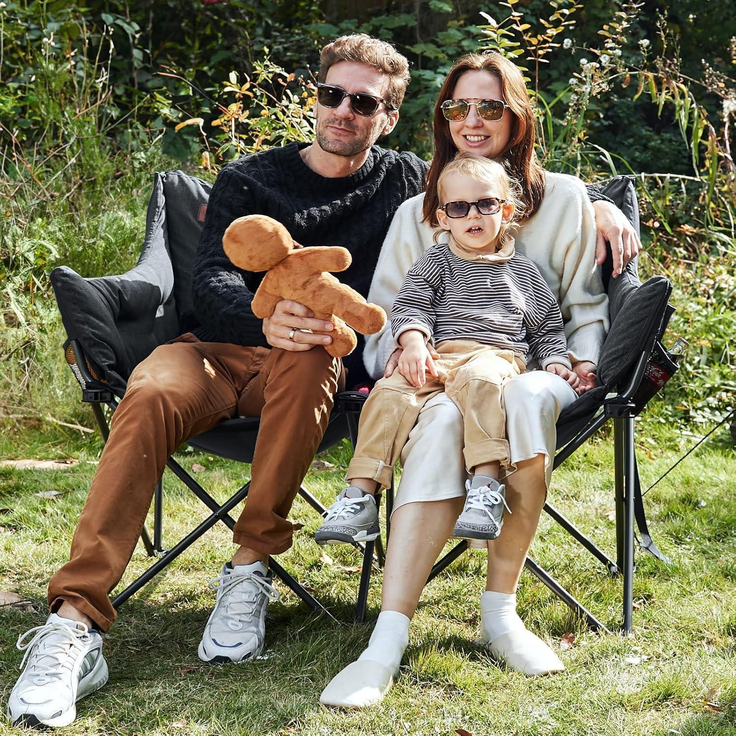 Una giovane famiglia siede insieme sulle sedie in giardino, tutti indossano occhiali da sole.