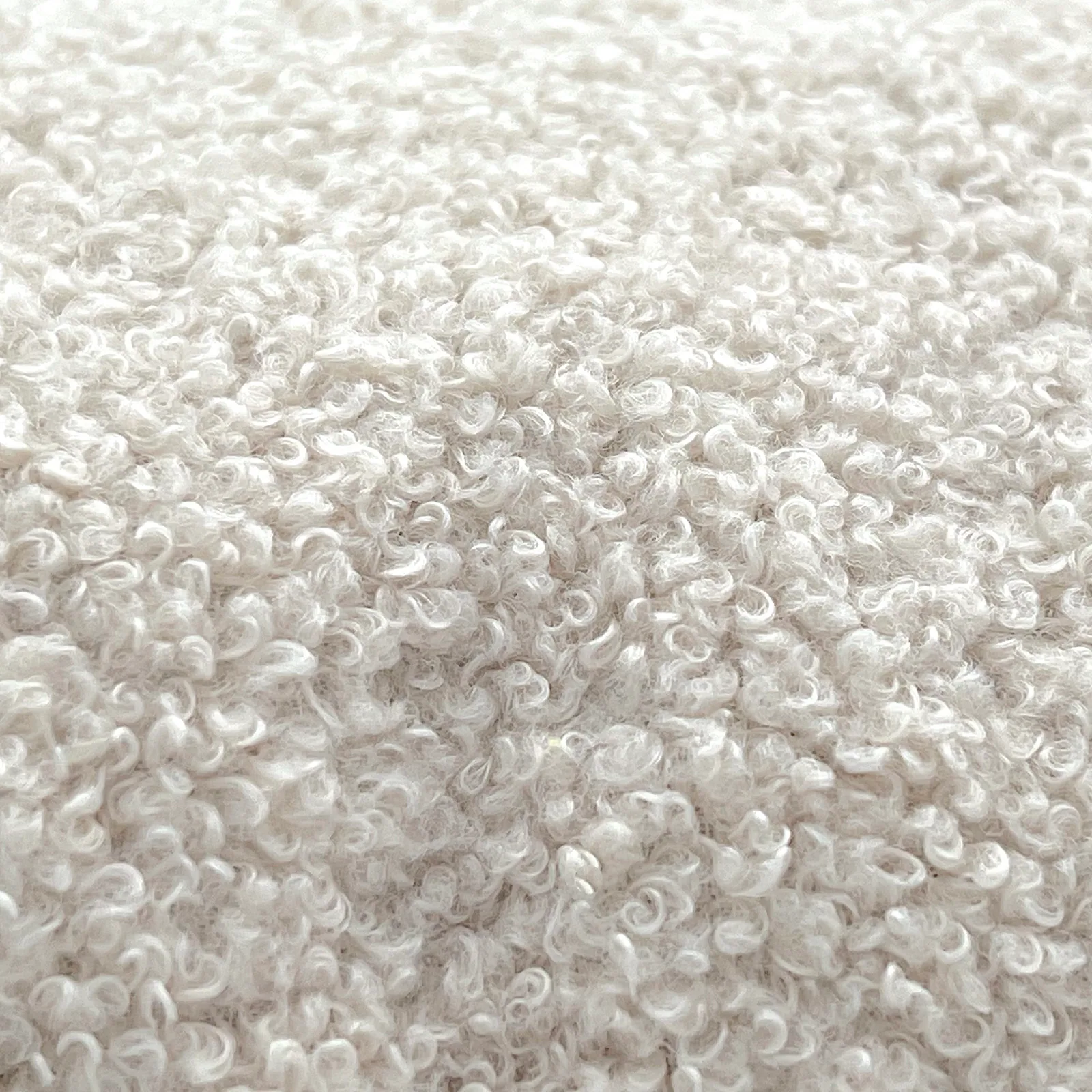 Nahaufnahme von weißem, flauschigem und lockigem Teddy-Stoff mit weicher Textur.
