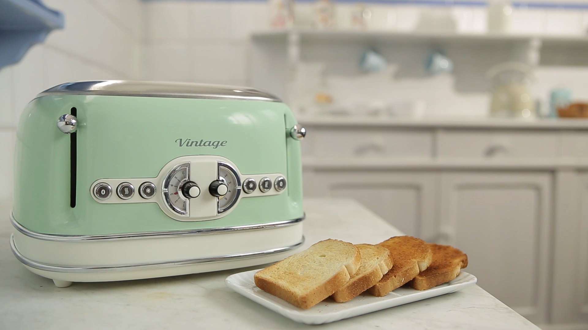 Ein mintgrüner Vintage-Toaster steht auf einer Küchenarbeitsplatte neben einem Teller mit vier Toastscheiben.