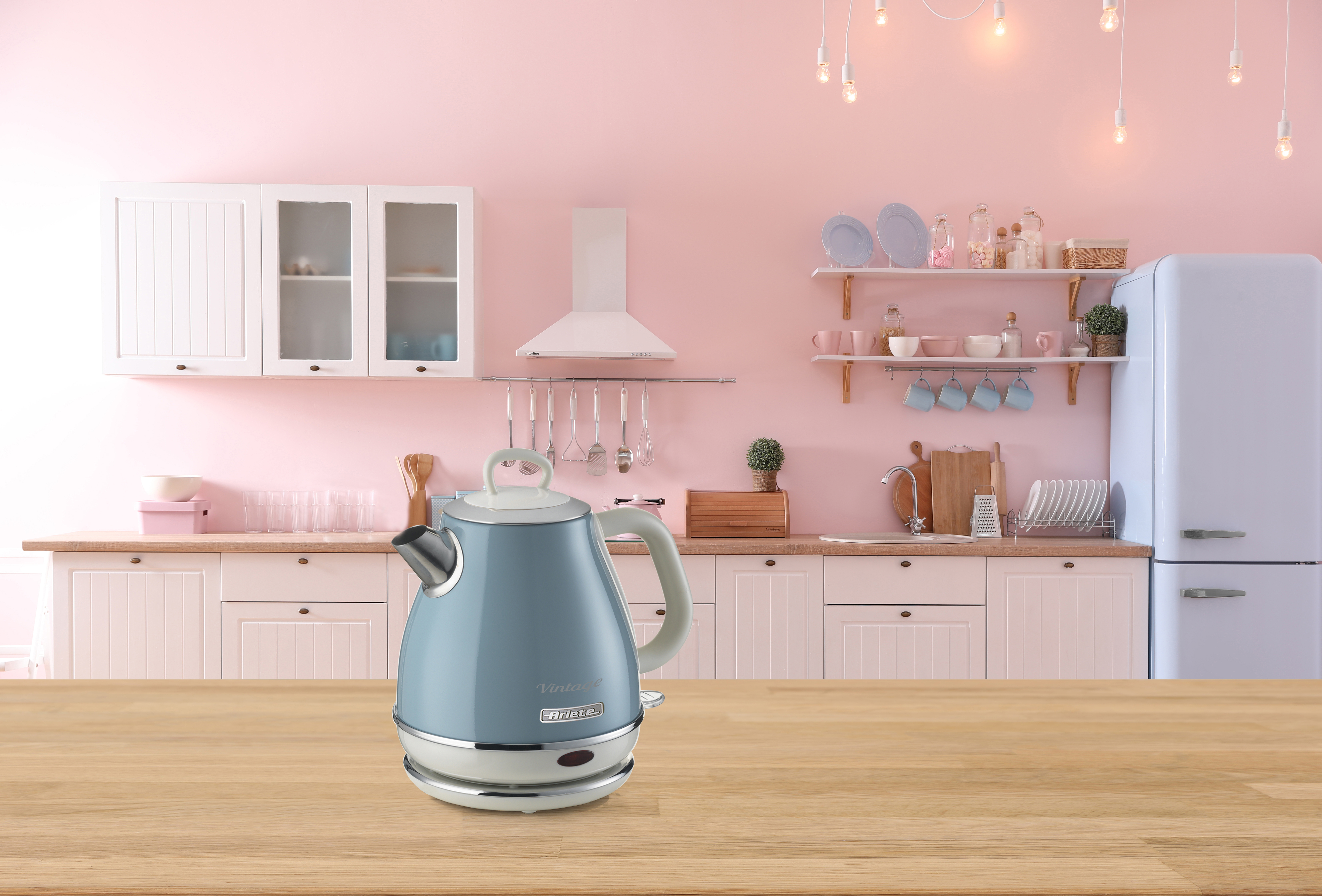A blue vintage kettle stands on a wooden table in a pink kitchen.