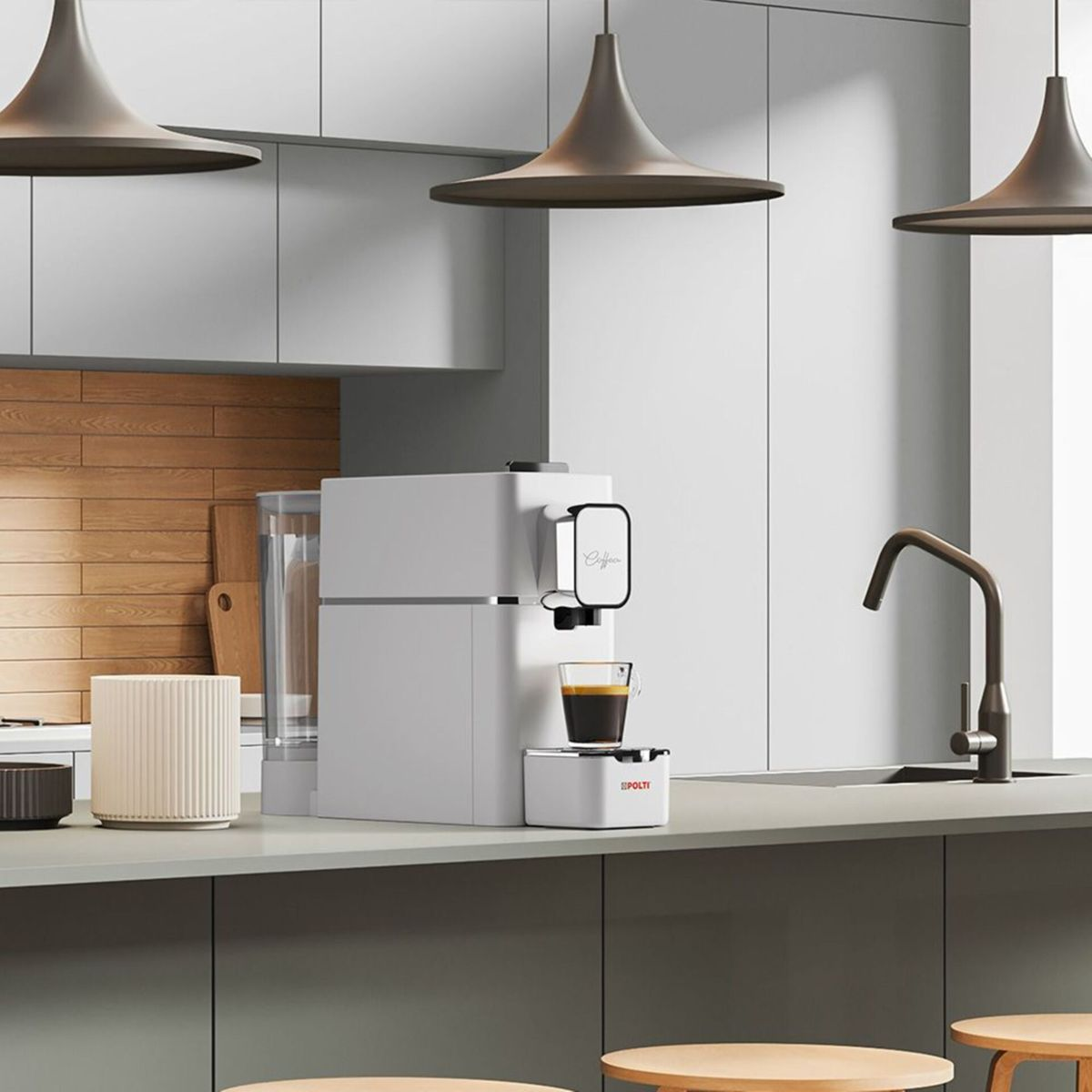 Eine weiße Kaffeemaschine steht auf einer modernen Küchenarbeitsplatte mit Hängeschränken und Pendelleuchten.