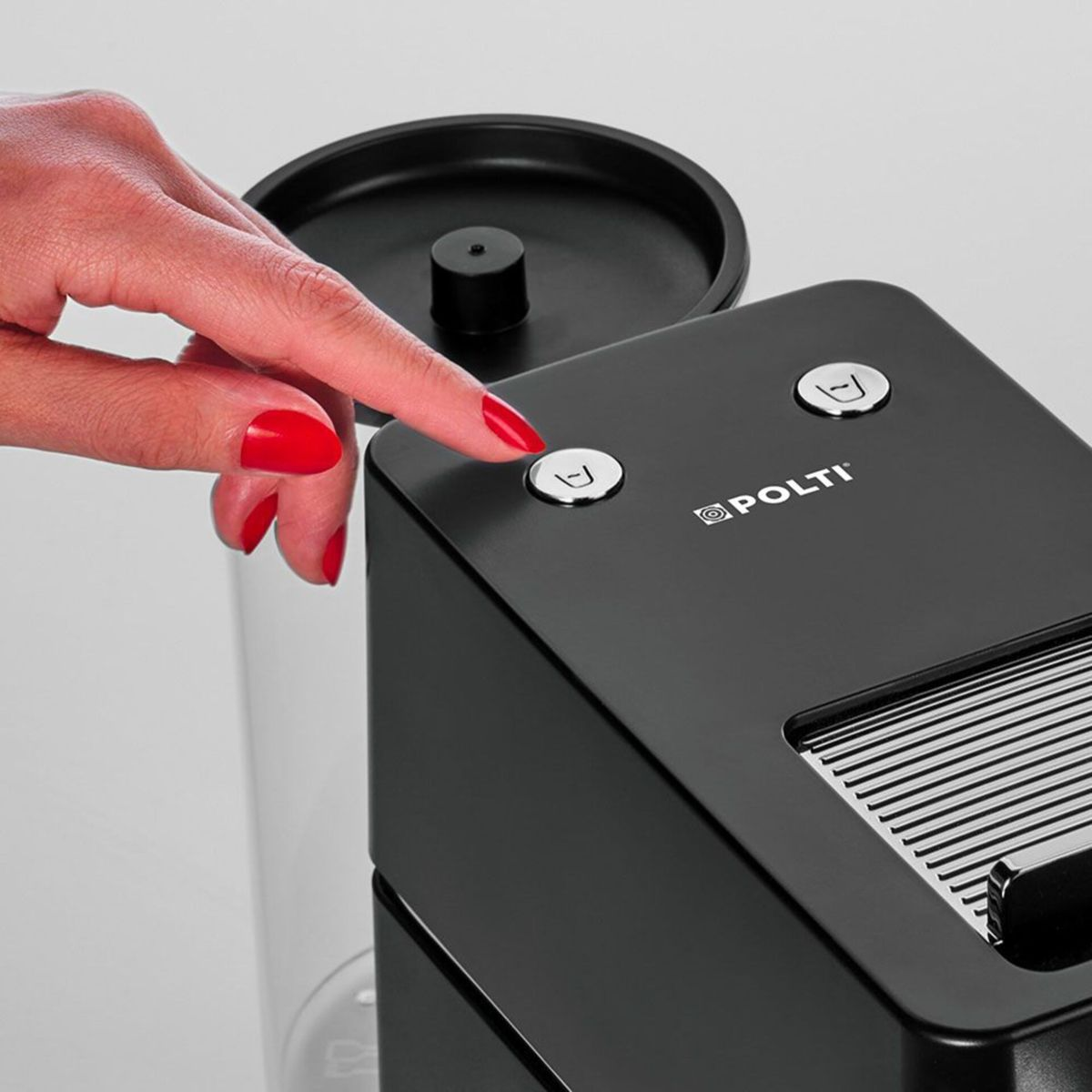 Eine Hand mit roten Fingernägeln drückt einen Knopf auf einer schwarzen Polti-Kaffeemaschine.