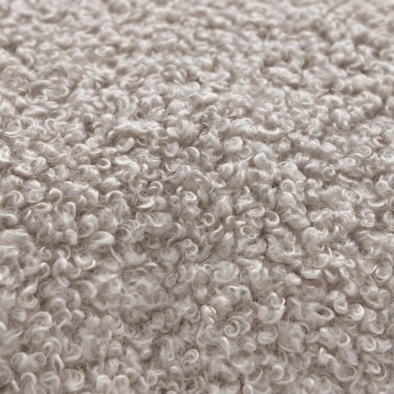 Nahaufnahme von weichem, hellgrauem Sherpa-Fleece-Stoff mit dichter, lockiger Textur.