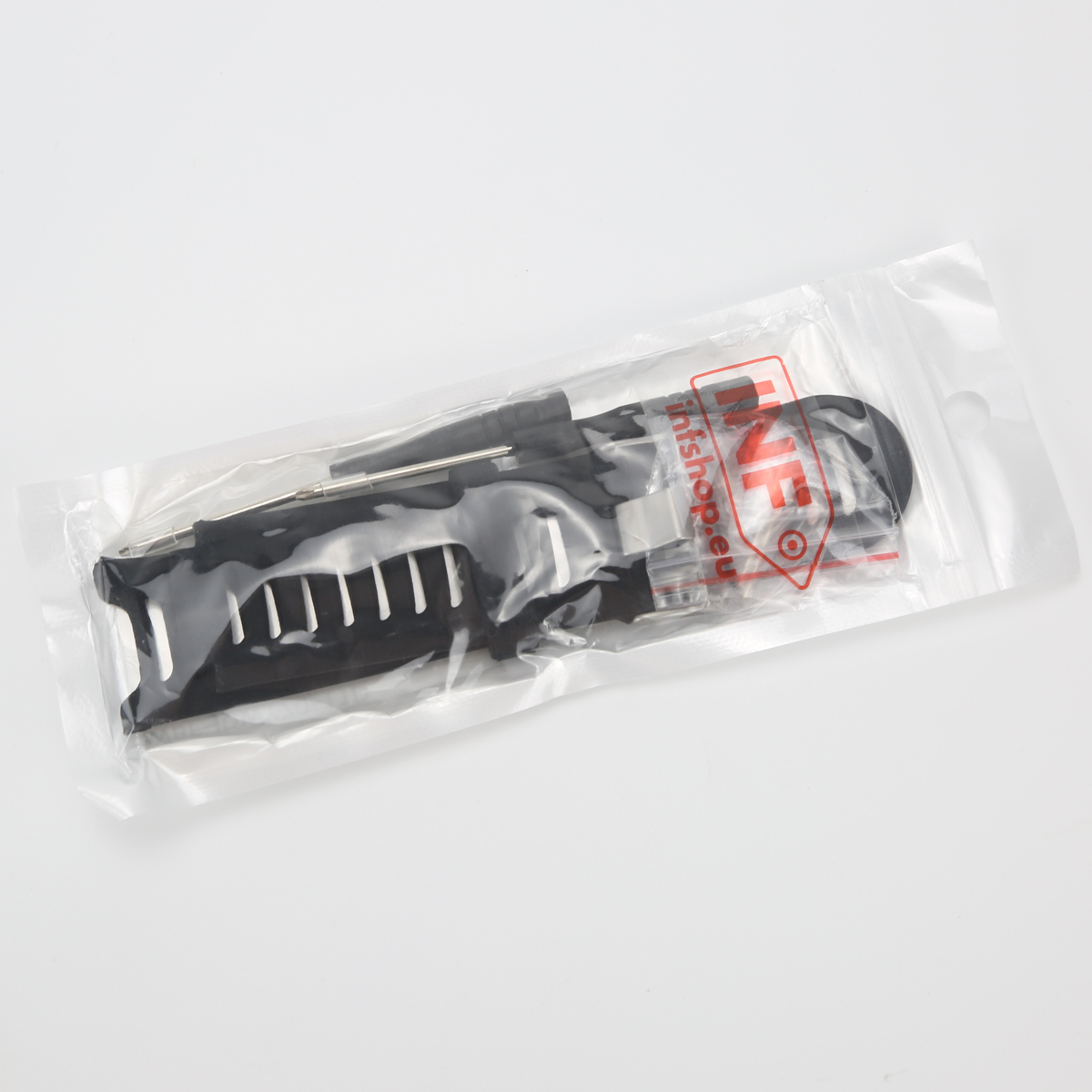 Ein schwarzes Uhrenarmband mit Werkzeugen in einer Plastiktüte auf weißem Grund.