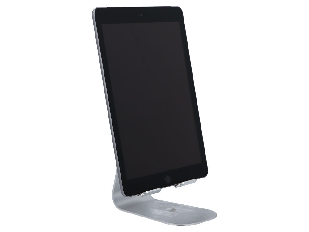 Czarny tablet stoi pionowo na srebrnym aluminiowym stojaku na białym tle.