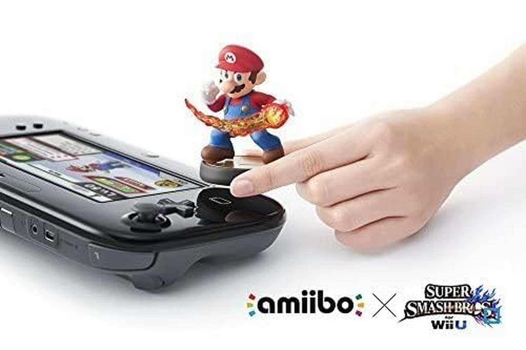 Eine Hand tippt auf den NFC-Bereich eines Wii U Gamepads, auf dem eine Mario amiibo-Figur steht.