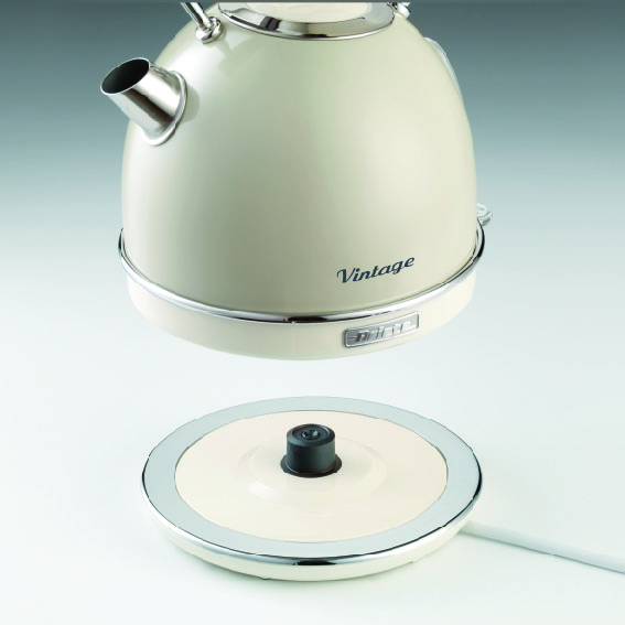 A cream-colored vintage electric kettle hovers above its round base.