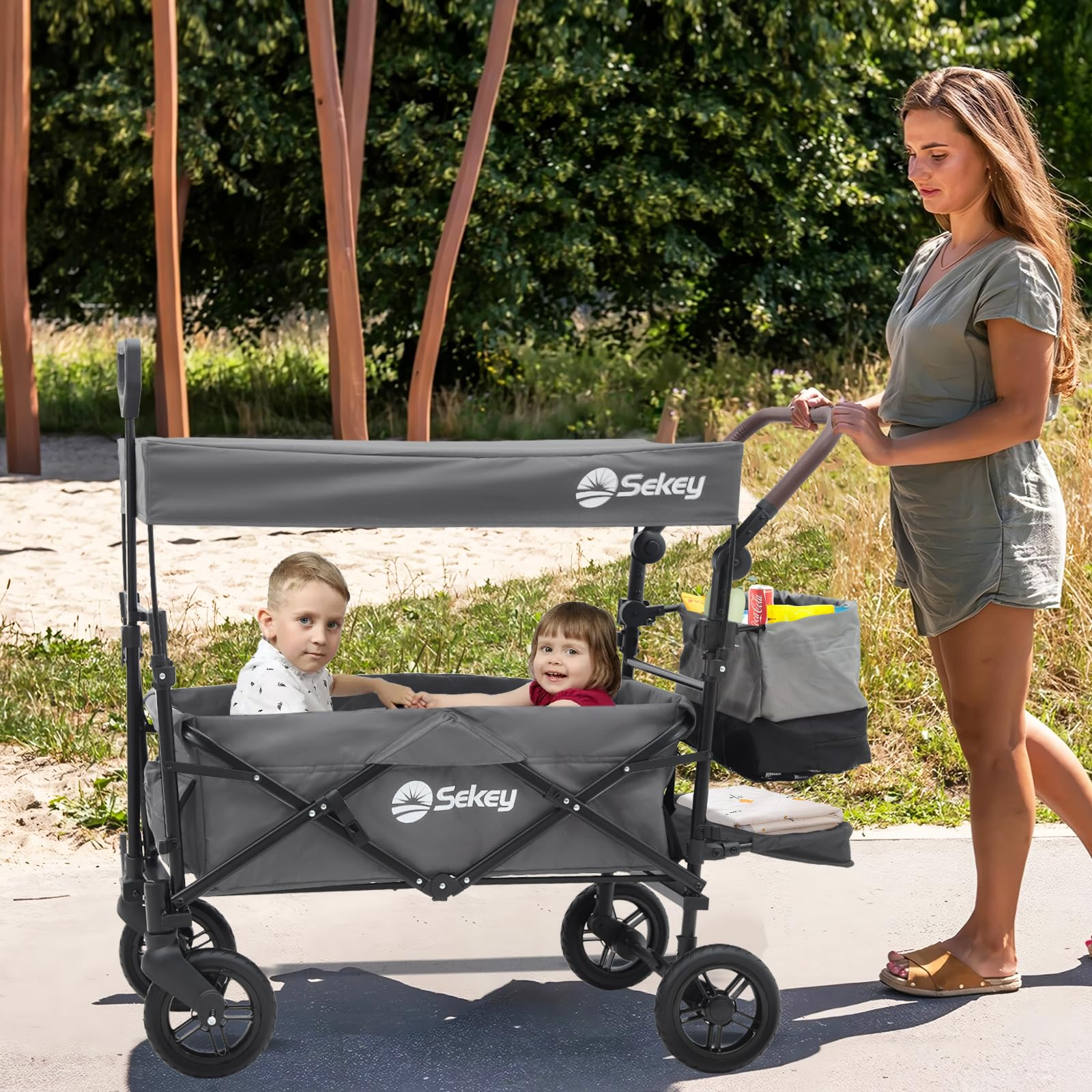 Une femme pousse un chariot gris Sekey transportant deux jeunes enfants sur un sentier.