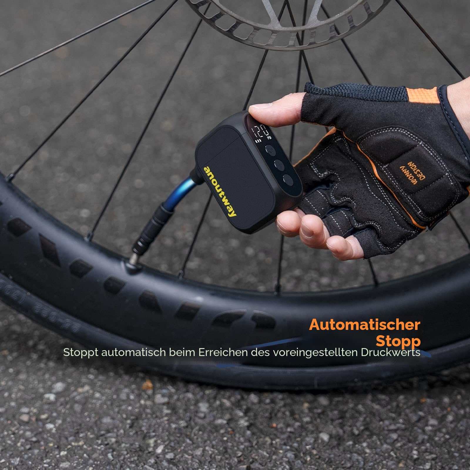 Hand mit Radfahrhandschuh nutzt eine kleine elektrische Pumpe, um einen Fahrradreifen aufzupumpen.