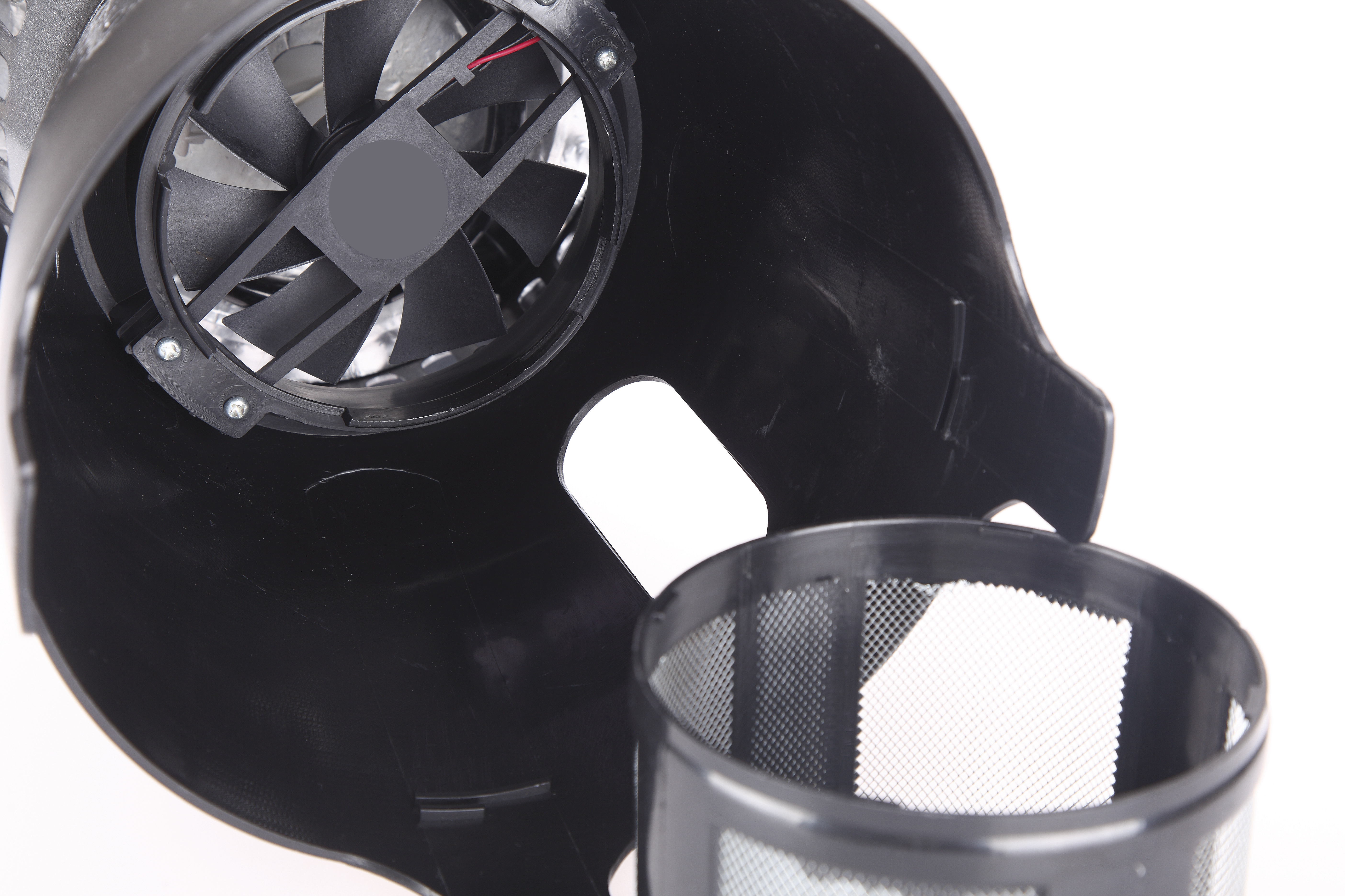 Una carcasa de plástico negro muestra un ventilador interno y un filtro de malla separado sobre fondo blanco.