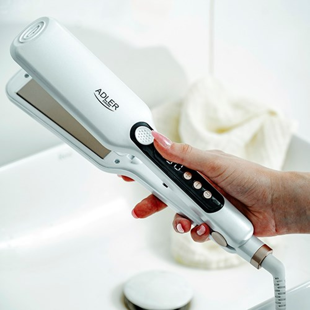 Una mano tiene una piastra per capelli bianca Adler sopra un lavandino.