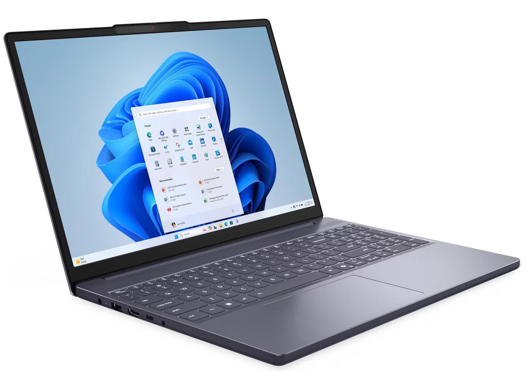 Szary laptop otwarty na białym tle, z niebieską tapetą i menu start.