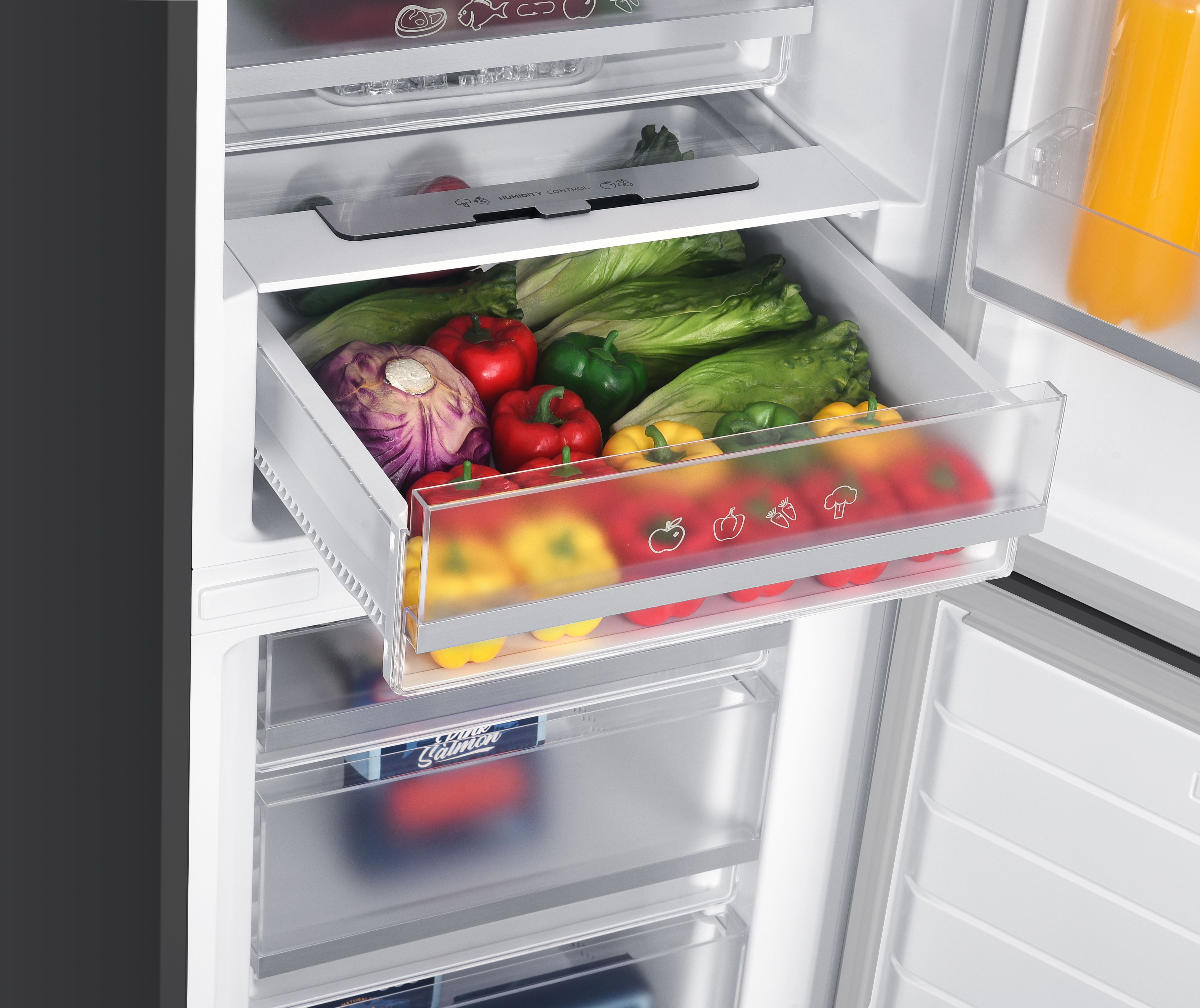 An open refrigerator vegetable drawer filled with fresh lettuce, bell peppers, and red cabbage.