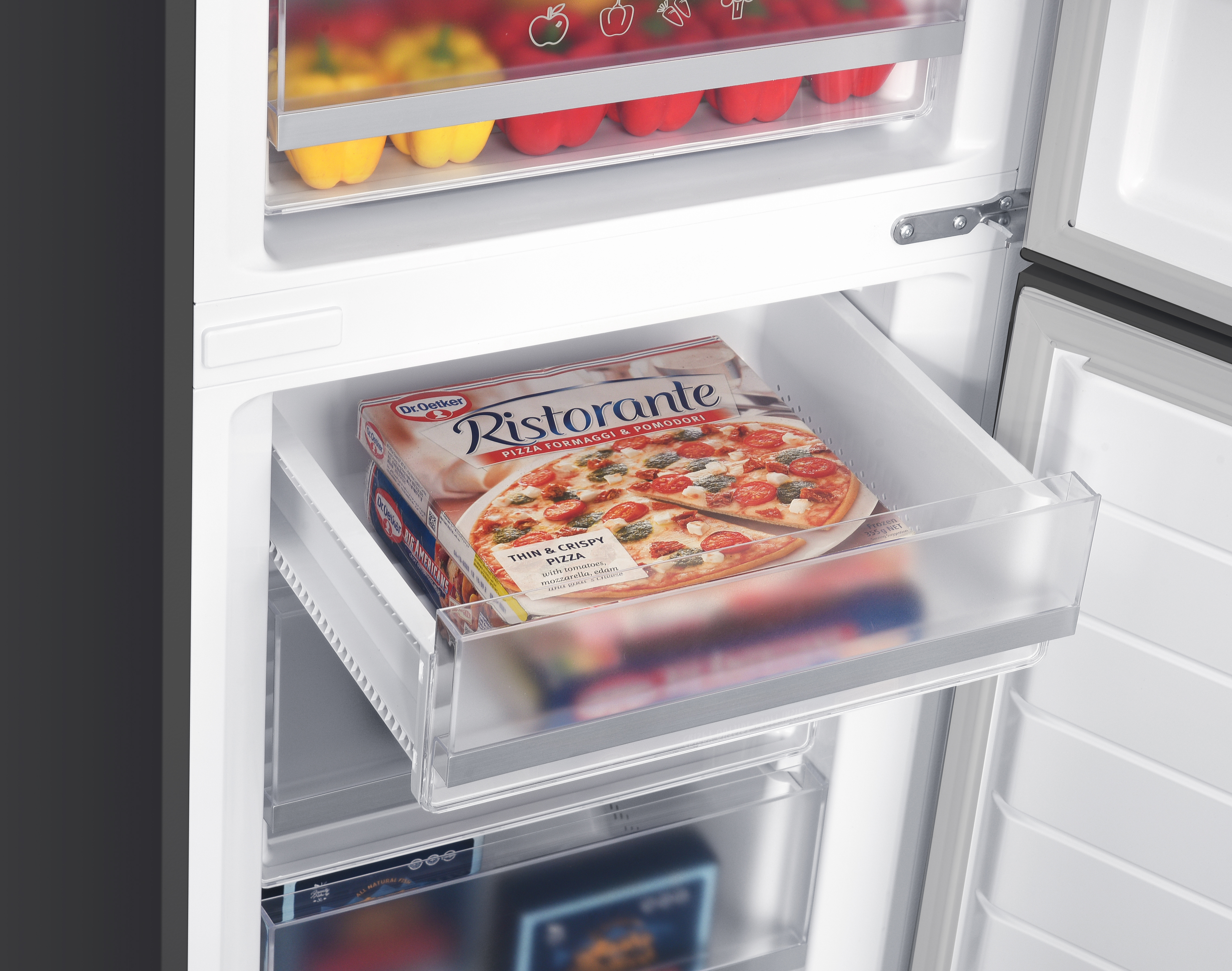 Open freezer with a Ristorante pizza box placed inside the upper transparent drawer.