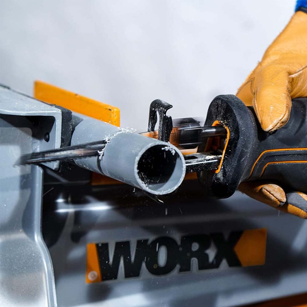 Eine Hand mit Handschuh schneidet mit einer Säge ein graues Rohr auf einer Workx-Werkbank.