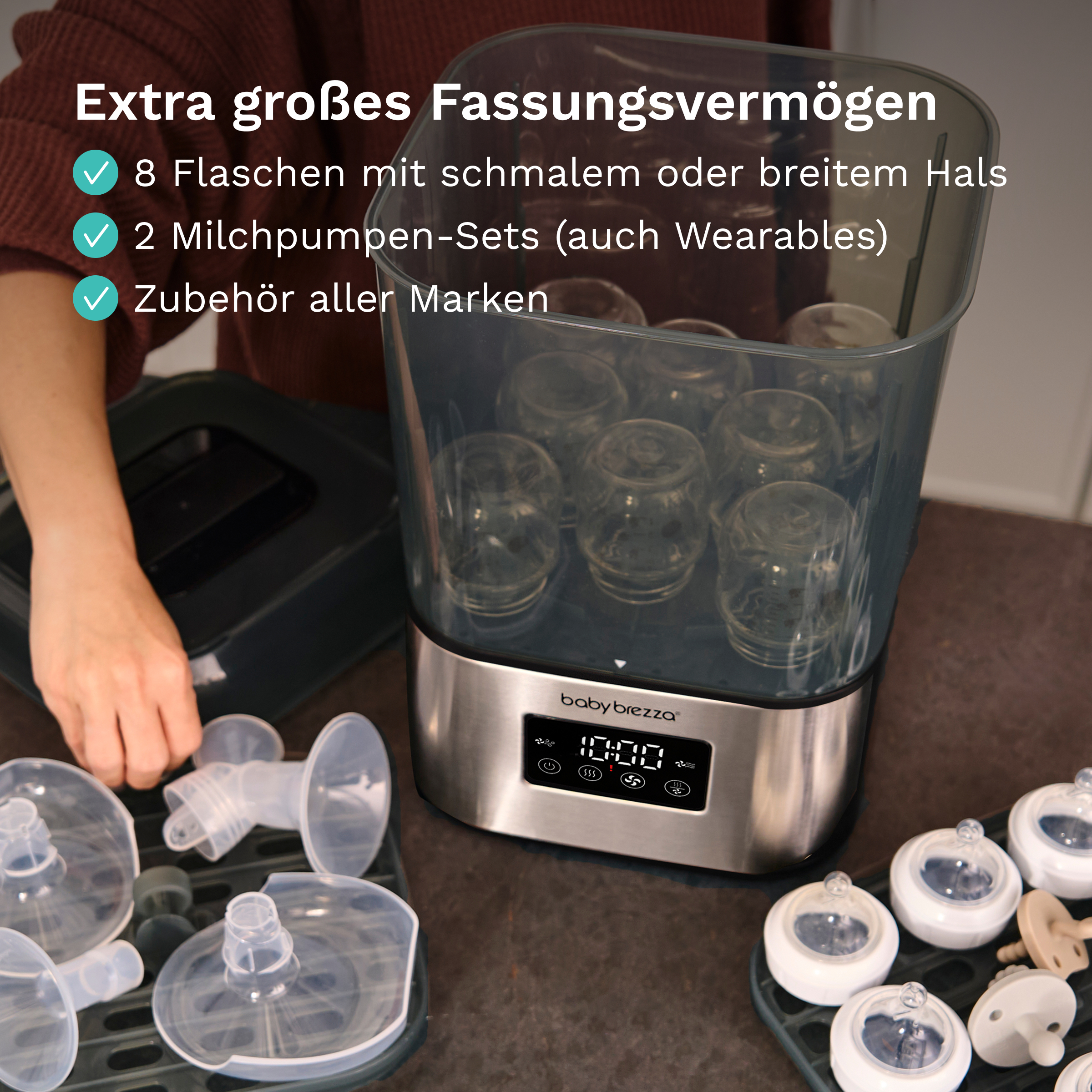 Ein Baby-Brezza-Sterilisator gefüllt mit Babyflaschen, Pumpteilen und weiteren Flaschen auf der Theke.