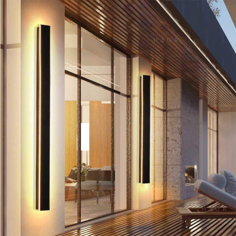 Moderne lange Wandleuchten mit warmem Licht an einer Glasfassade eines Hauses.