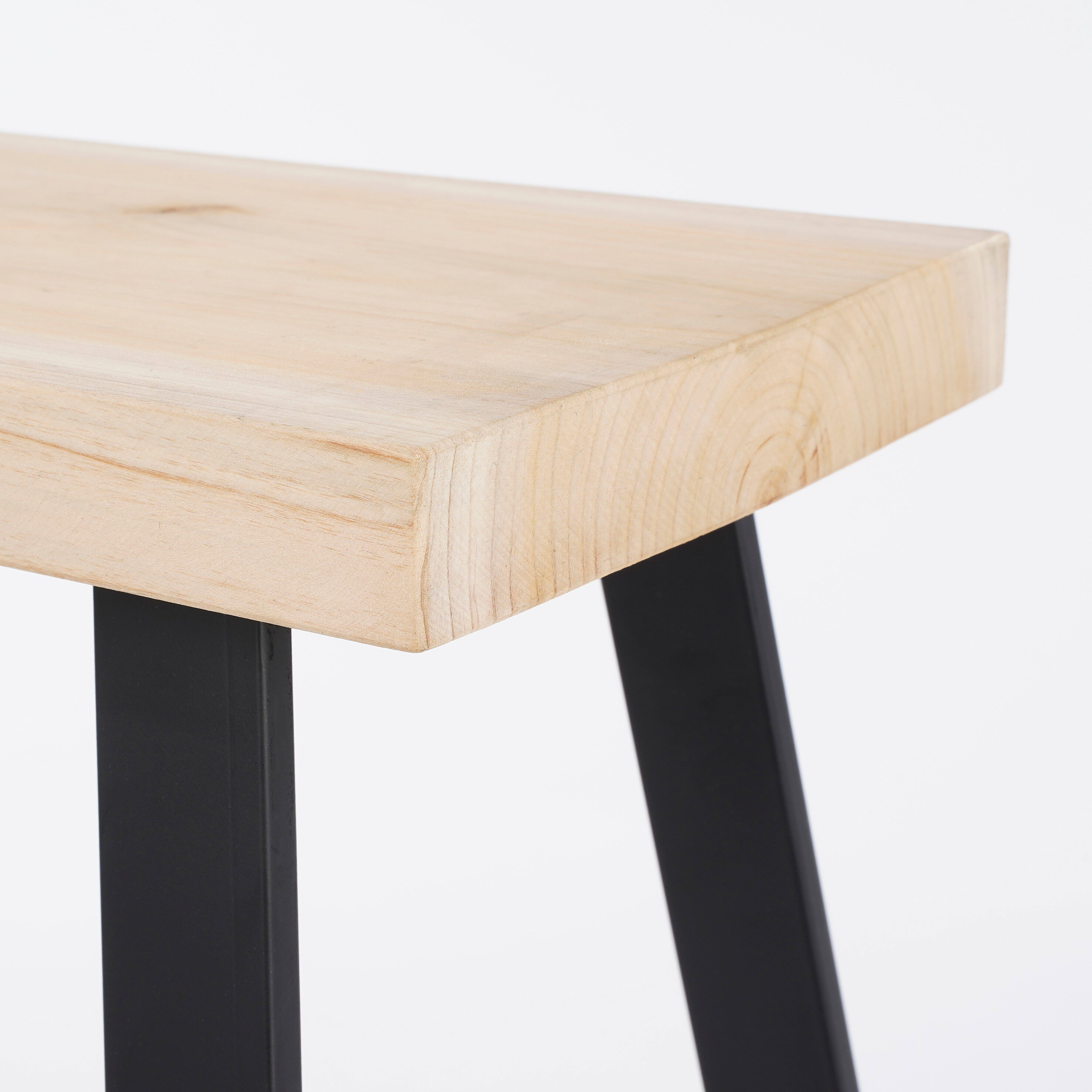 Eine Holzbank mit dicker heller Holzplatte und schwarzen Metallbeinen vor weißem Hintergrund.
