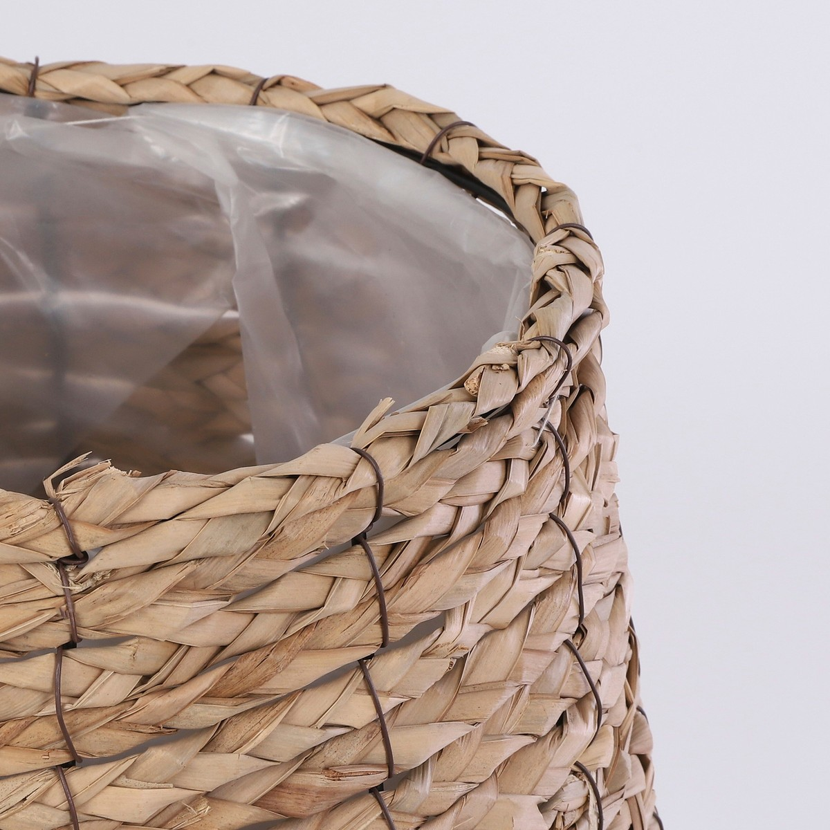 Ein gewebter Naturfaser Korb mit Plastikeinsatz auf weissem Grund.