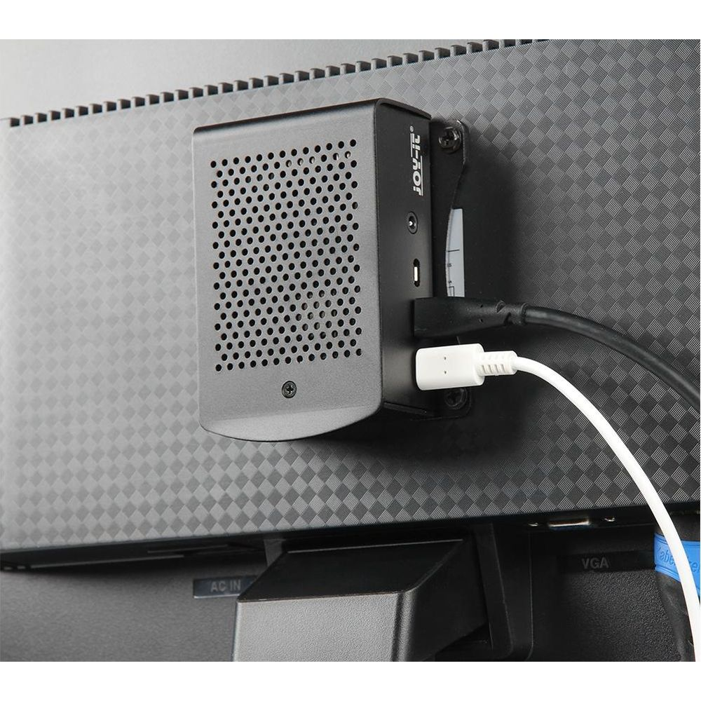 Un mini PC nero fissato sul retro di un monitor con cavi collegati.