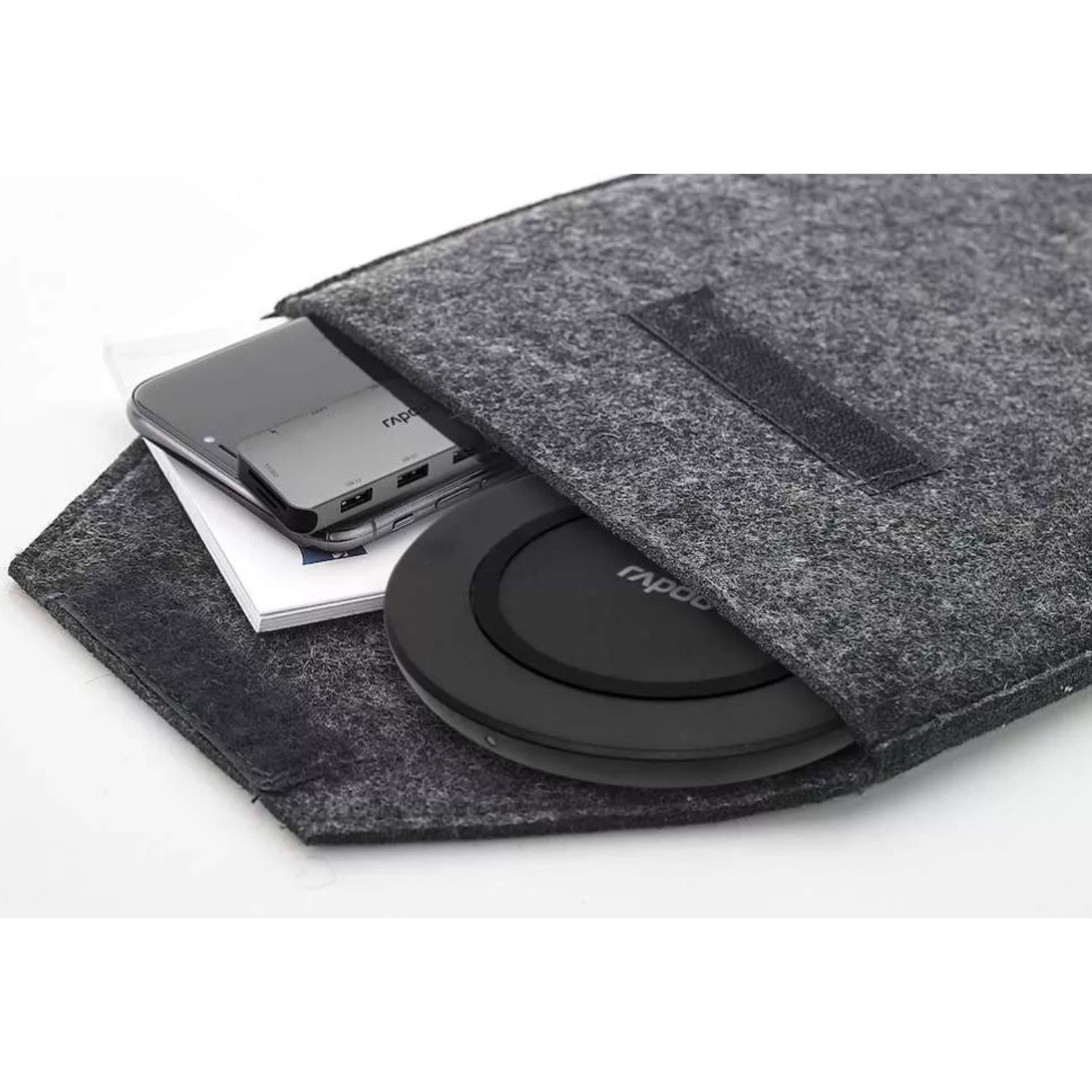 A grey felt bag holds a smartphone, a USB hub, and a black wireless charger.