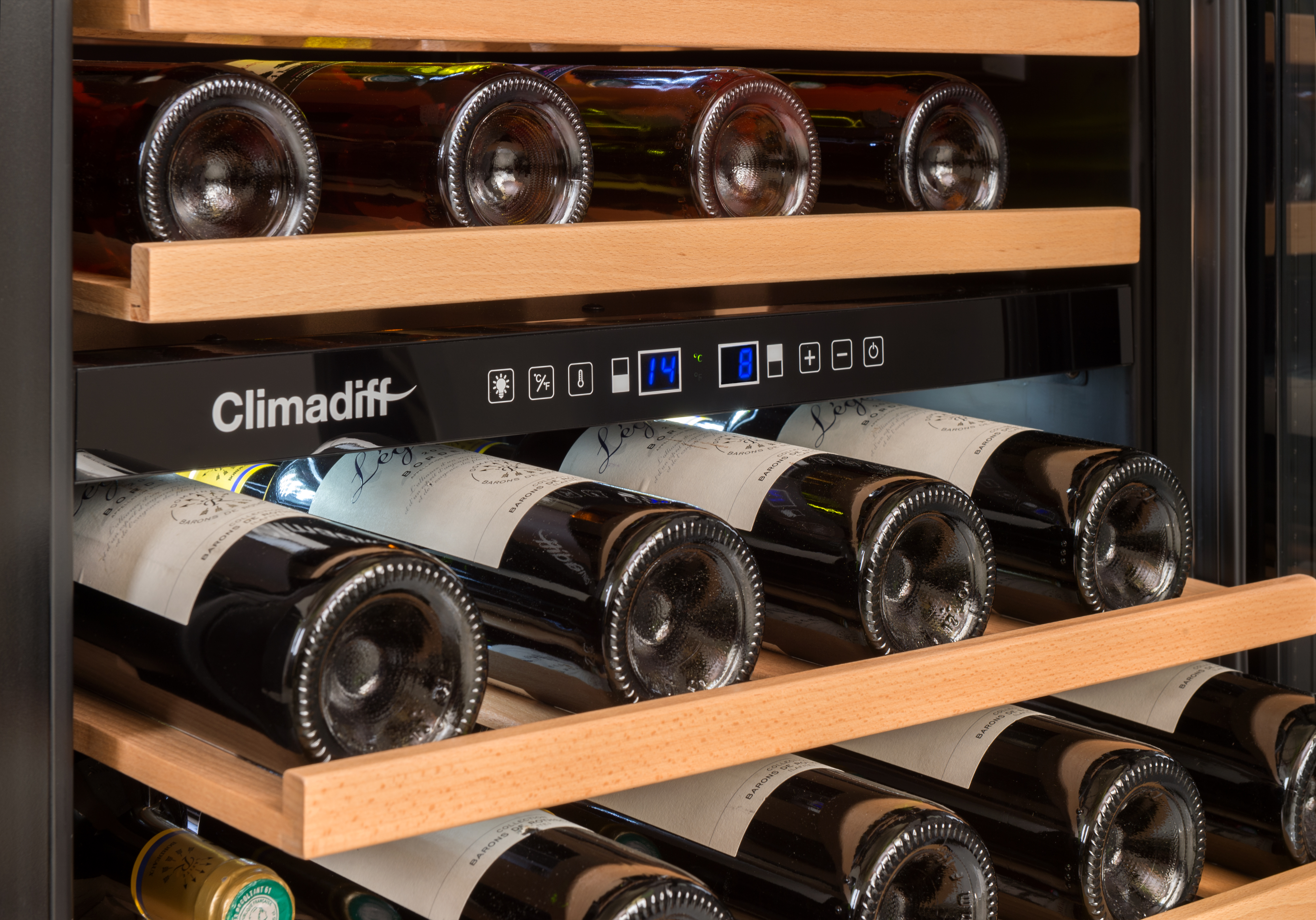 Gros plan d'une cave à vin Climadiff avec des étagères en bois, des bouteilles de vin et un panneau de contrôle.