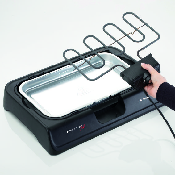 A hand placing a heating element into a black and silver electric grill.