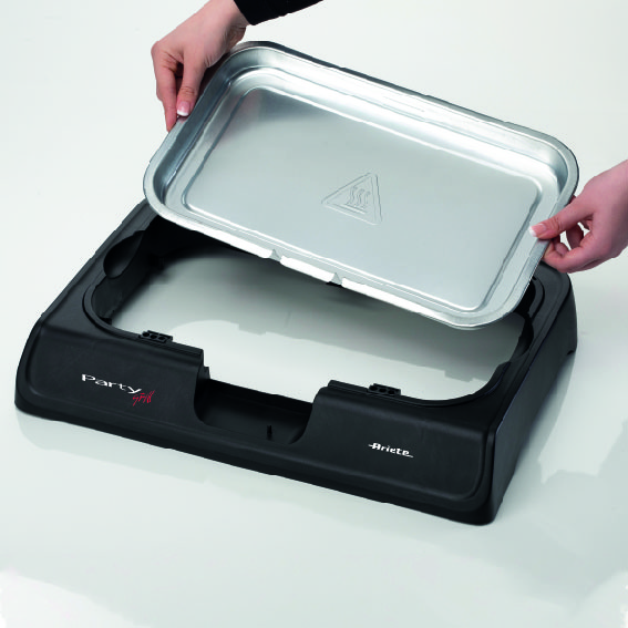 Hands hold a silver tray above a black party grill base.