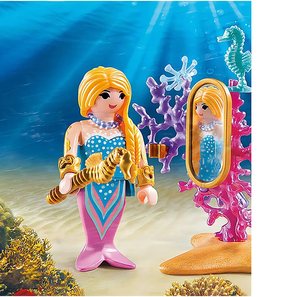 Una figura de sirena de Playmobil está bajo el agua junto a un espejo de coral, sosteniendo un caballito de mar dorado.
