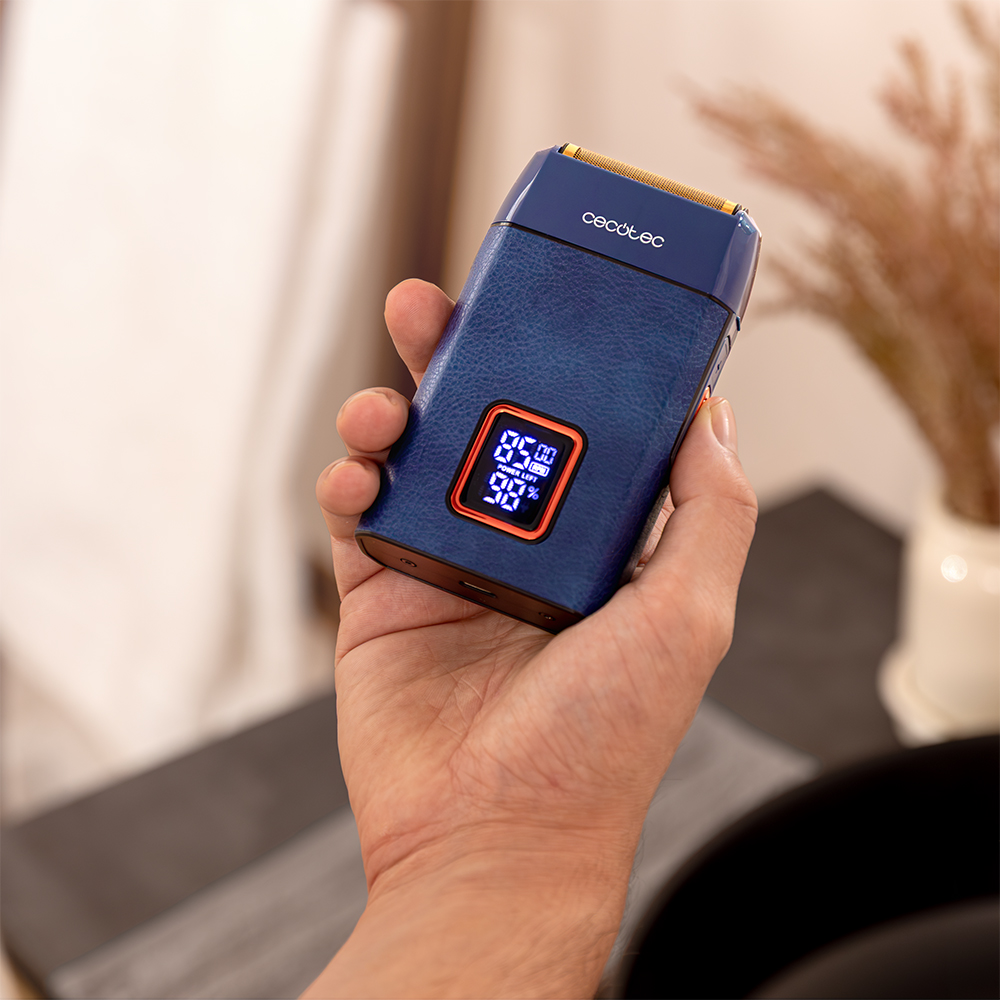 Una mano sostiene una afeitadora eléctrica azul con pantalla digital.