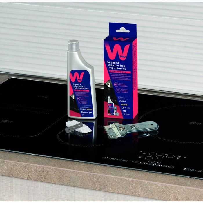 Kit pulizia per piani cottura in vetroceramica e a induzione Wpro con flacone, scatola, raschietto e lame su un piano cottura.