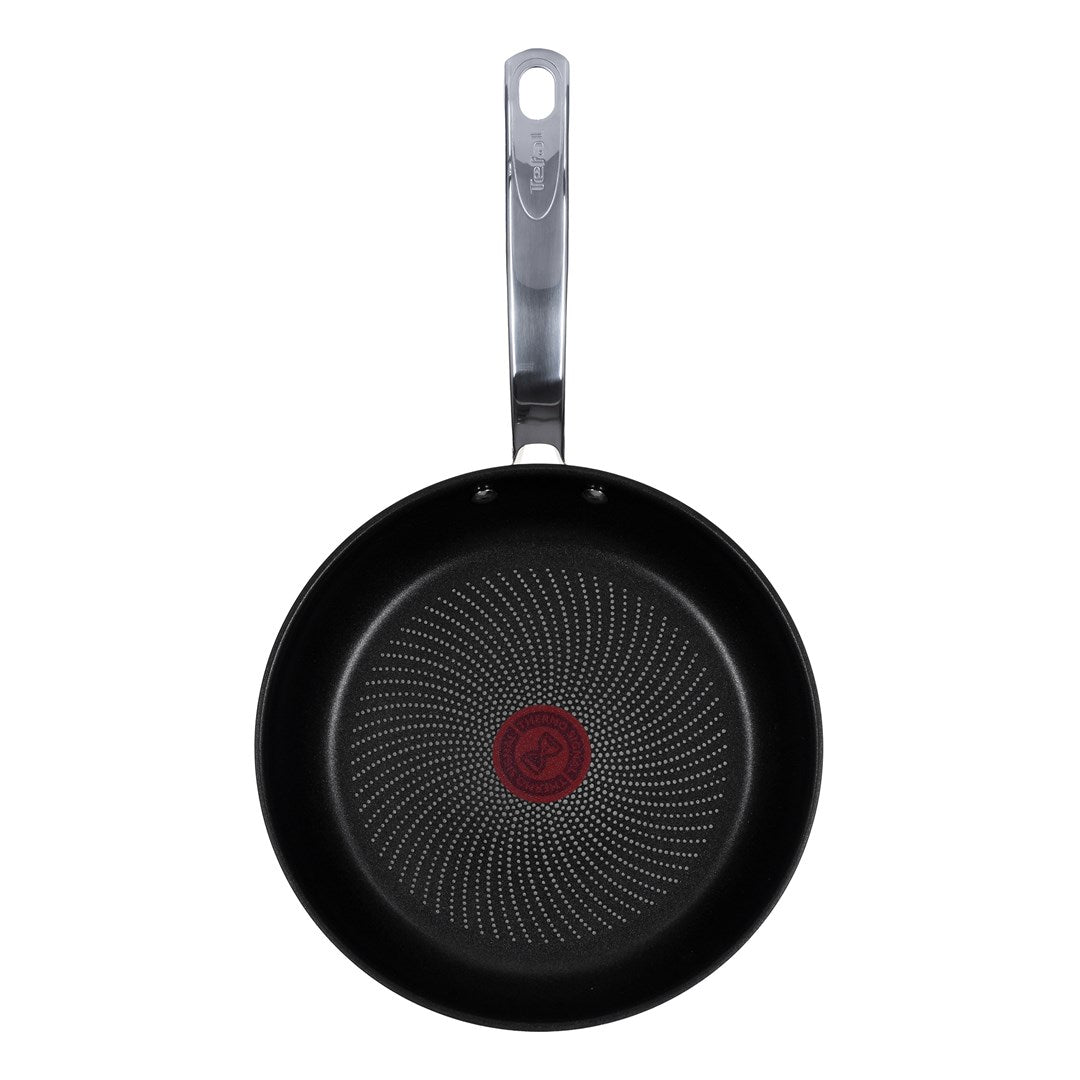 Top view of a black Tefal frying pan with a silver handle and a red spot in the center.