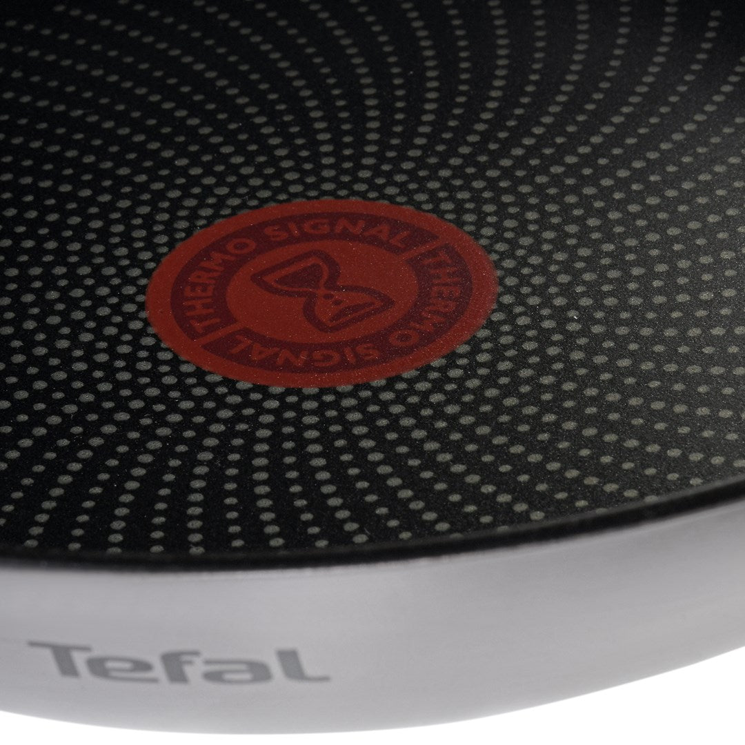 Close-up of a Tefal frying pan showing the red thermo signal in the center of the non-stick surface.