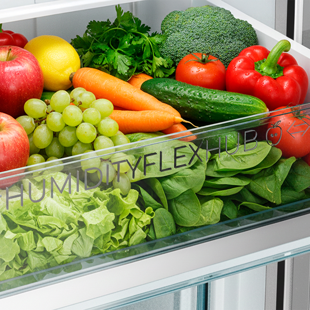 Cajón de verduras de un refrigerador lleno de frutas, verduras y hierbas frescas.