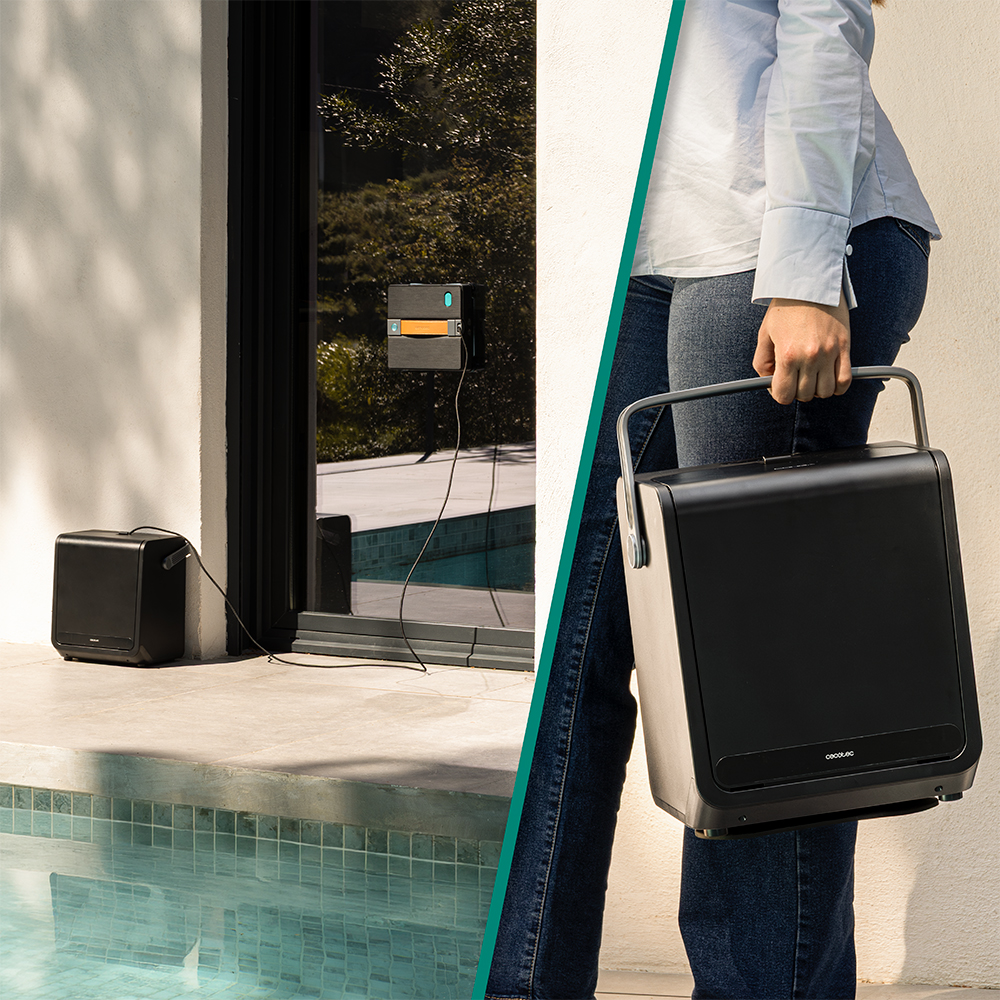 Una persona sostiene un limpiaventanas robot negro con asa junto a una piscina y una casa.