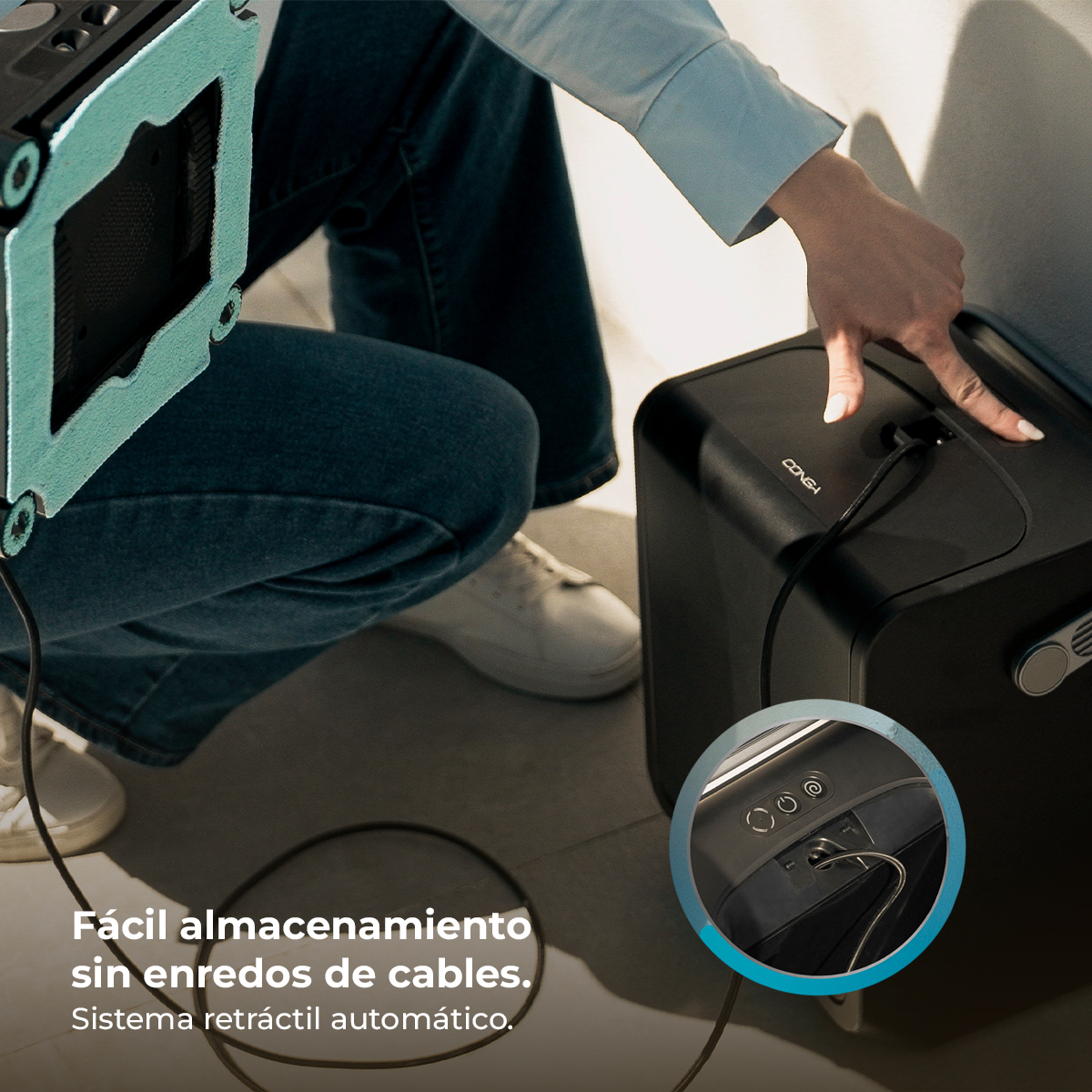 Persona presionando el botón de inicio de un dispositivo negro, con un robot limpiador.