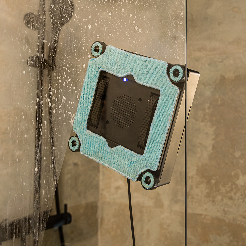 Un limpiador de ventanas automático con microfibra turquesa limpia un panel de vidrio.