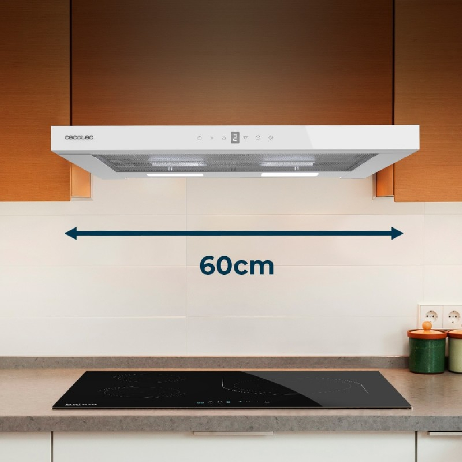 Una campana extractora blanca de 60 cm cuelga sobre una placa de inducción negra en una cocina de madera.